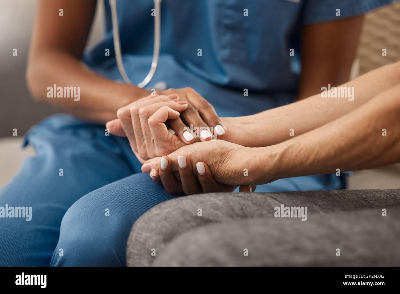 Its okay if youre not feeling okay. Shot of a doctor holding hands with her patient during a consultation at home. Stock Photo