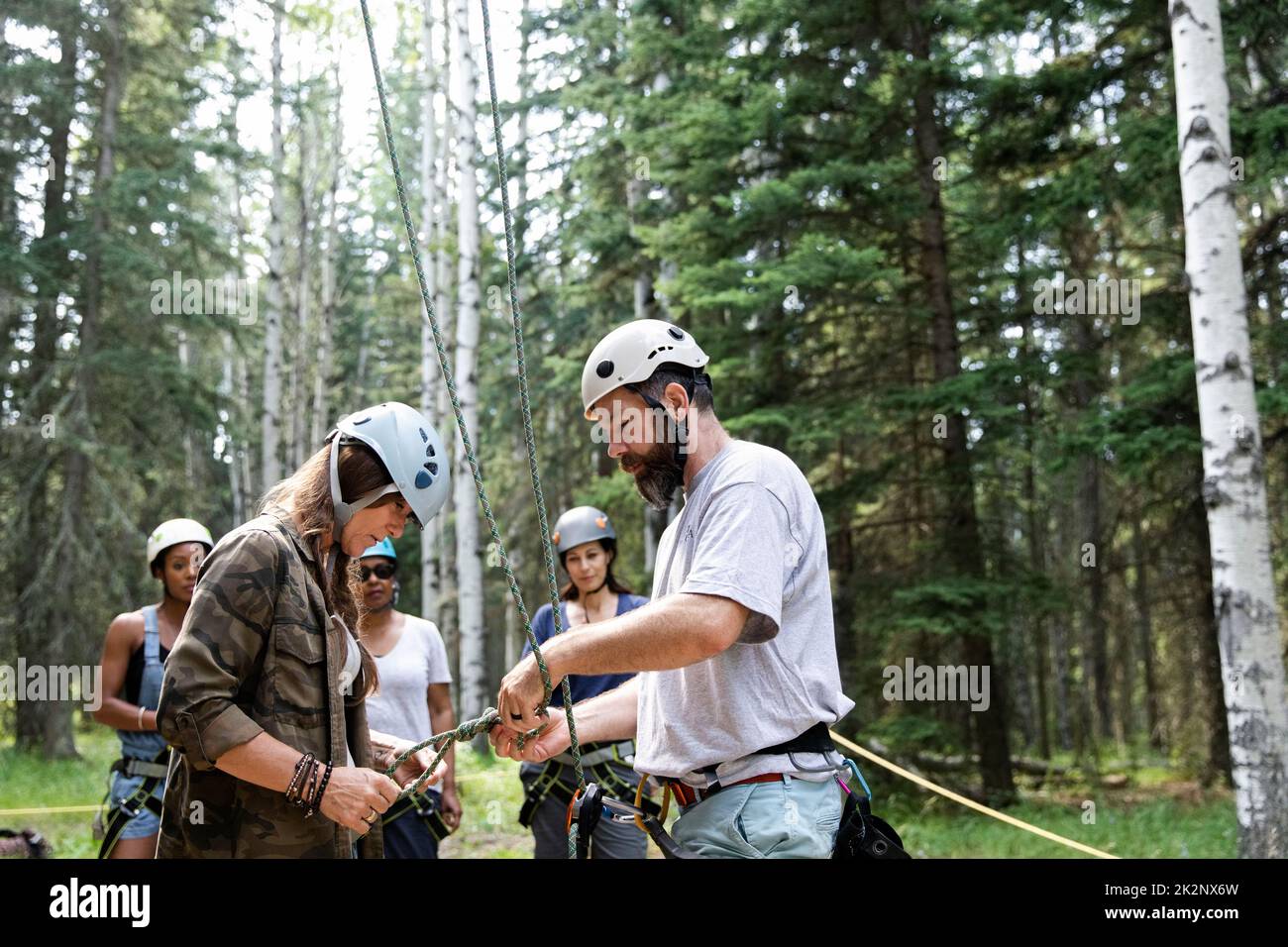 Instructor attaching ropes to woman's climbing harness Stock Photo Alamy