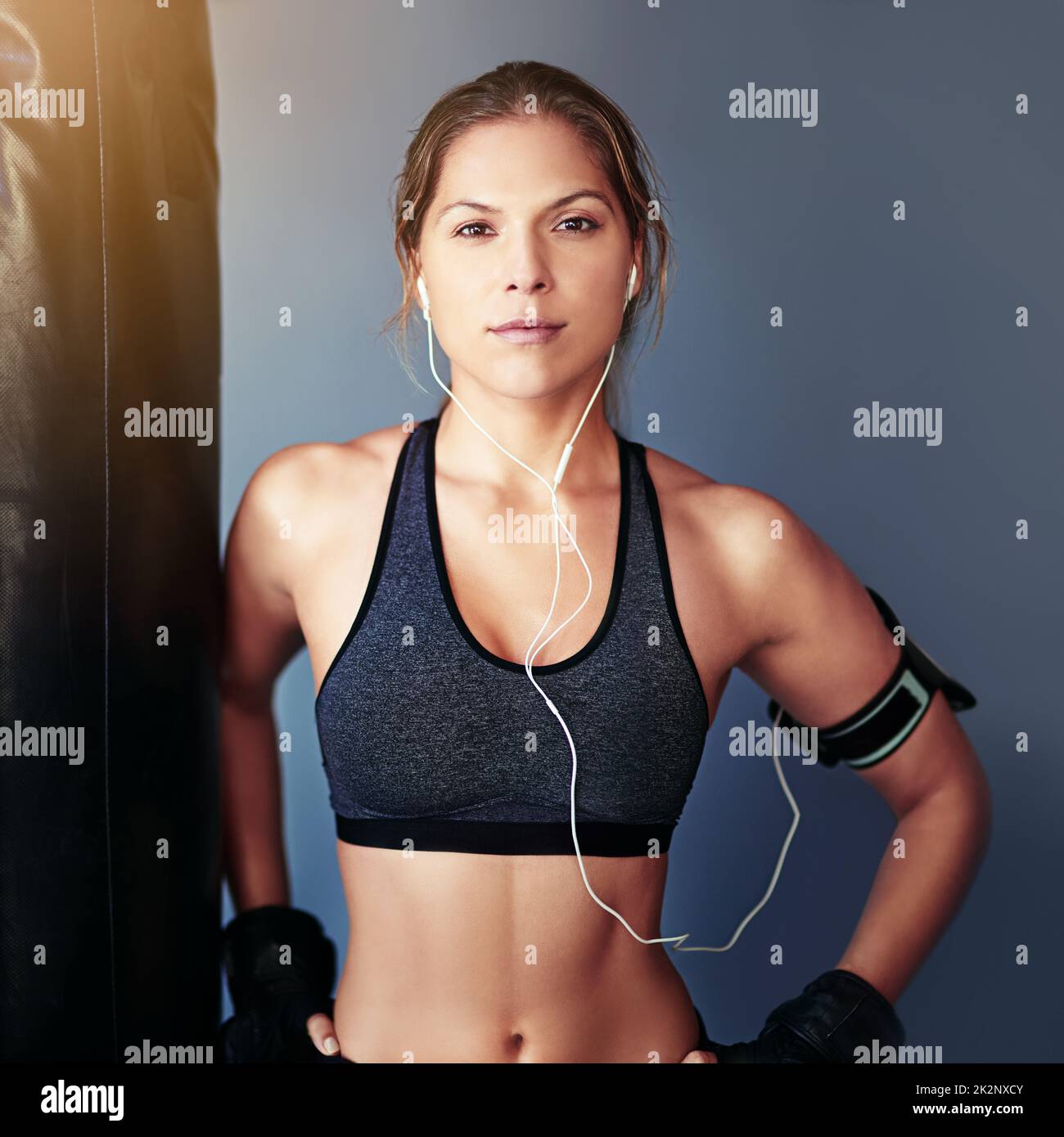 Ready for any challenge. Portrait of a female boxer standing beside a punching bag. Stock Photo
