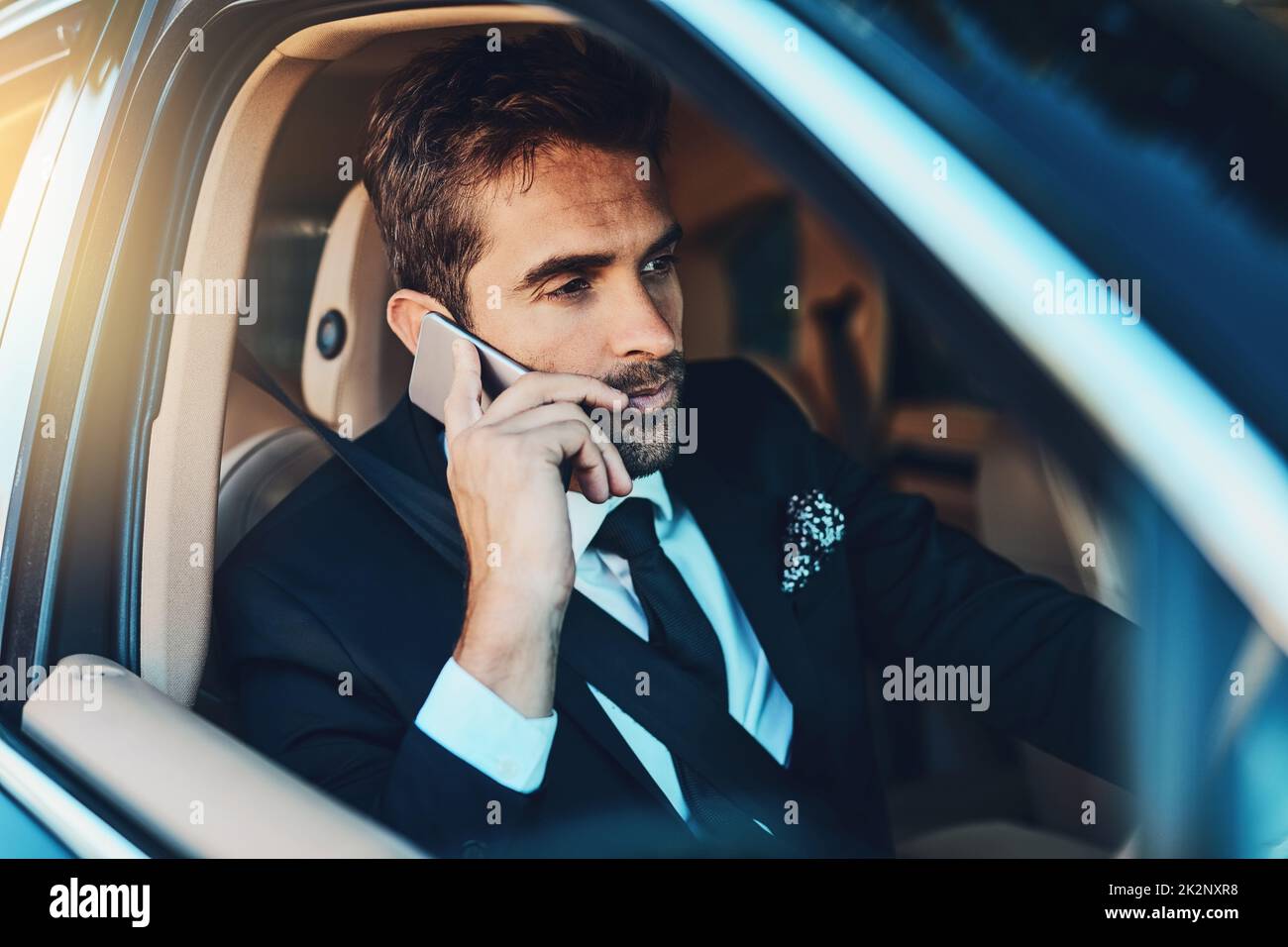 I cannot take this call, Im driving. Cropped shot of a handsome young corporate businessman on a call while commuting. Stock Photo