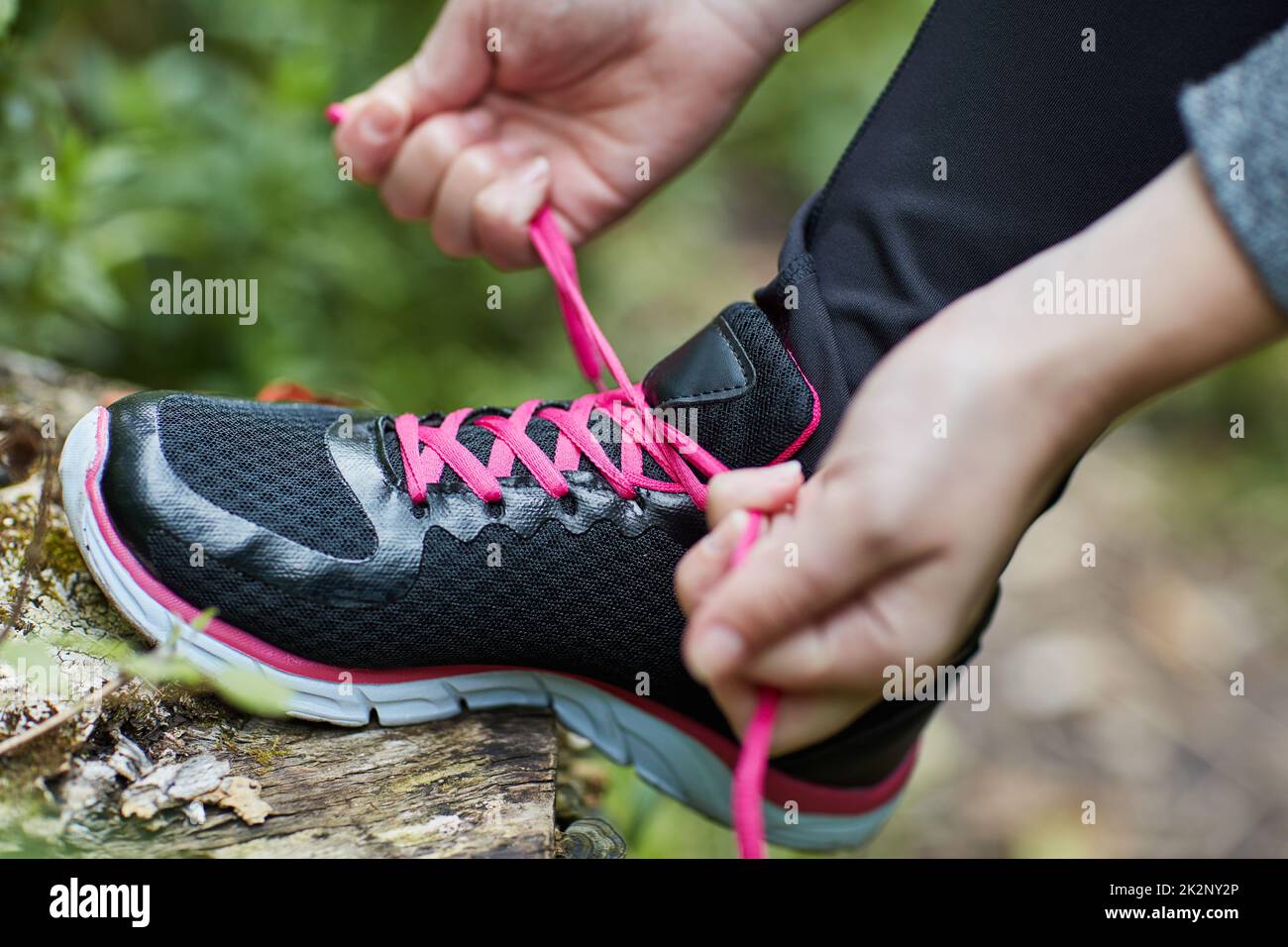 Laced up and ready to go. Shot of an unidentifiable young woman tying her shoelaces while hiking in the forest. Stock Photo