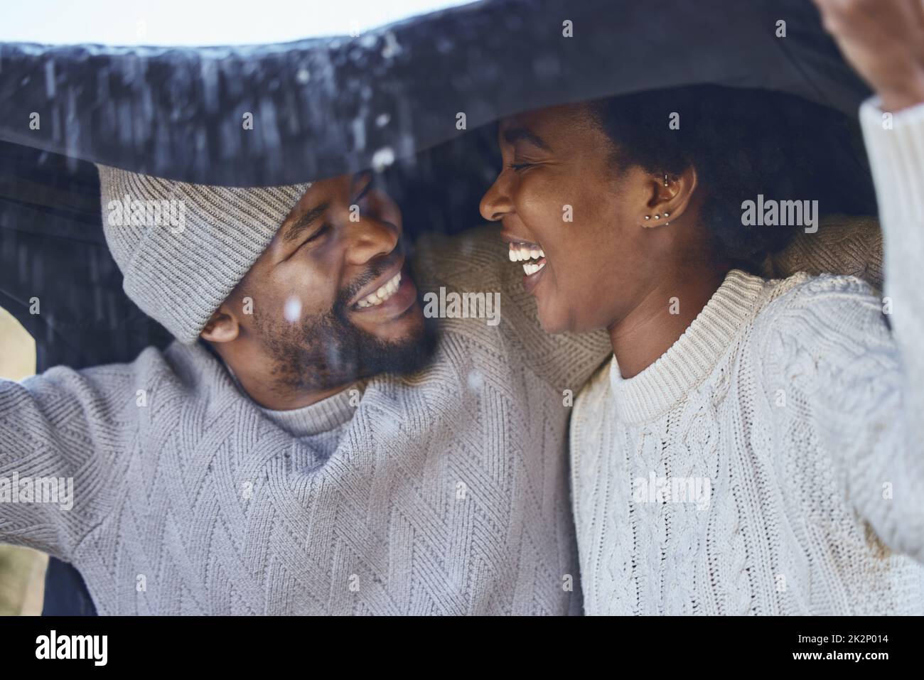 Baby its cold outside. Shot of a young couple protecting themselves from the rain. Stock Photo