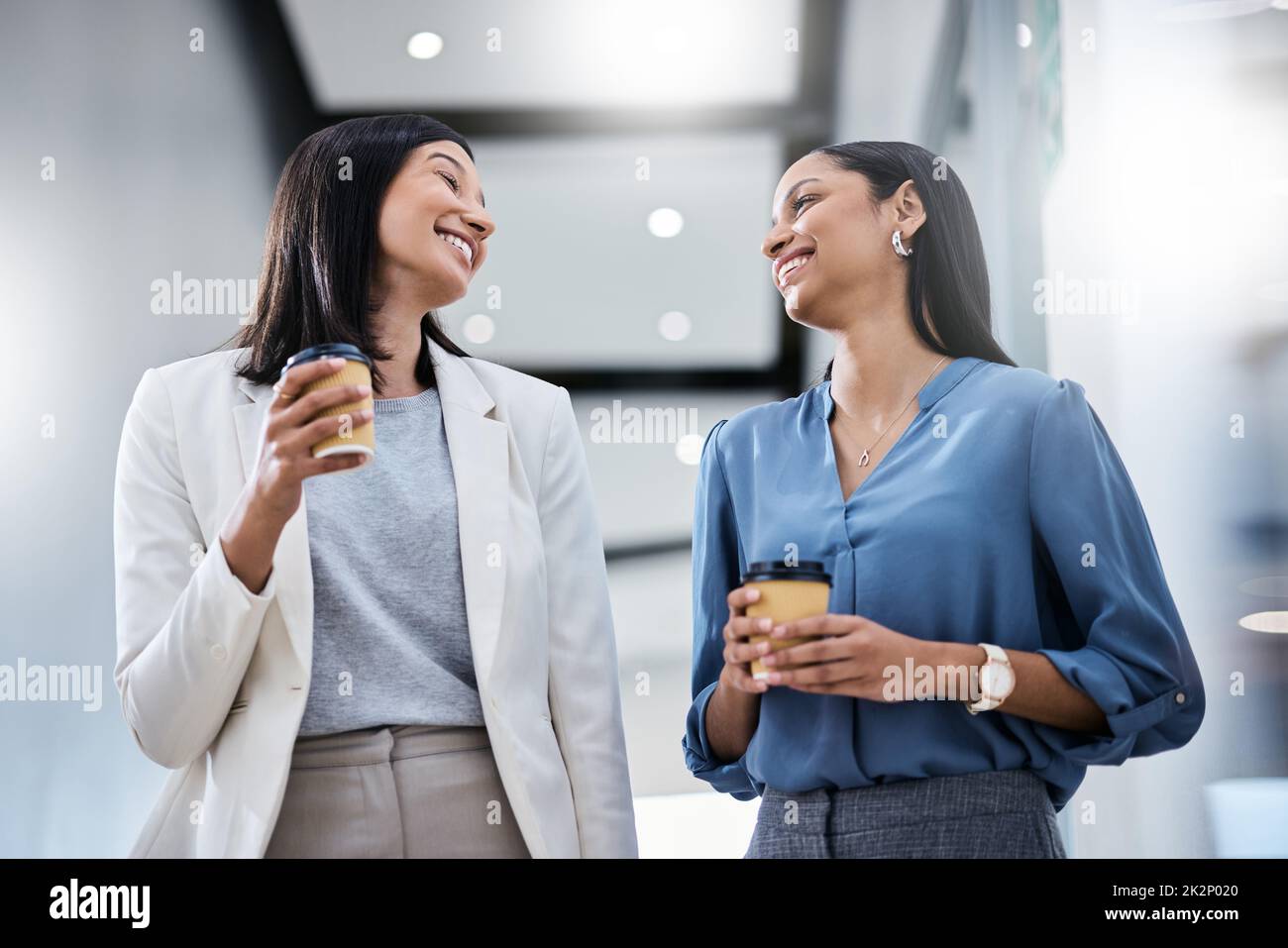 They told us that we couldnt, so we did. Shot of two businesswomen holding coffees while talking in an office. Stock Photo