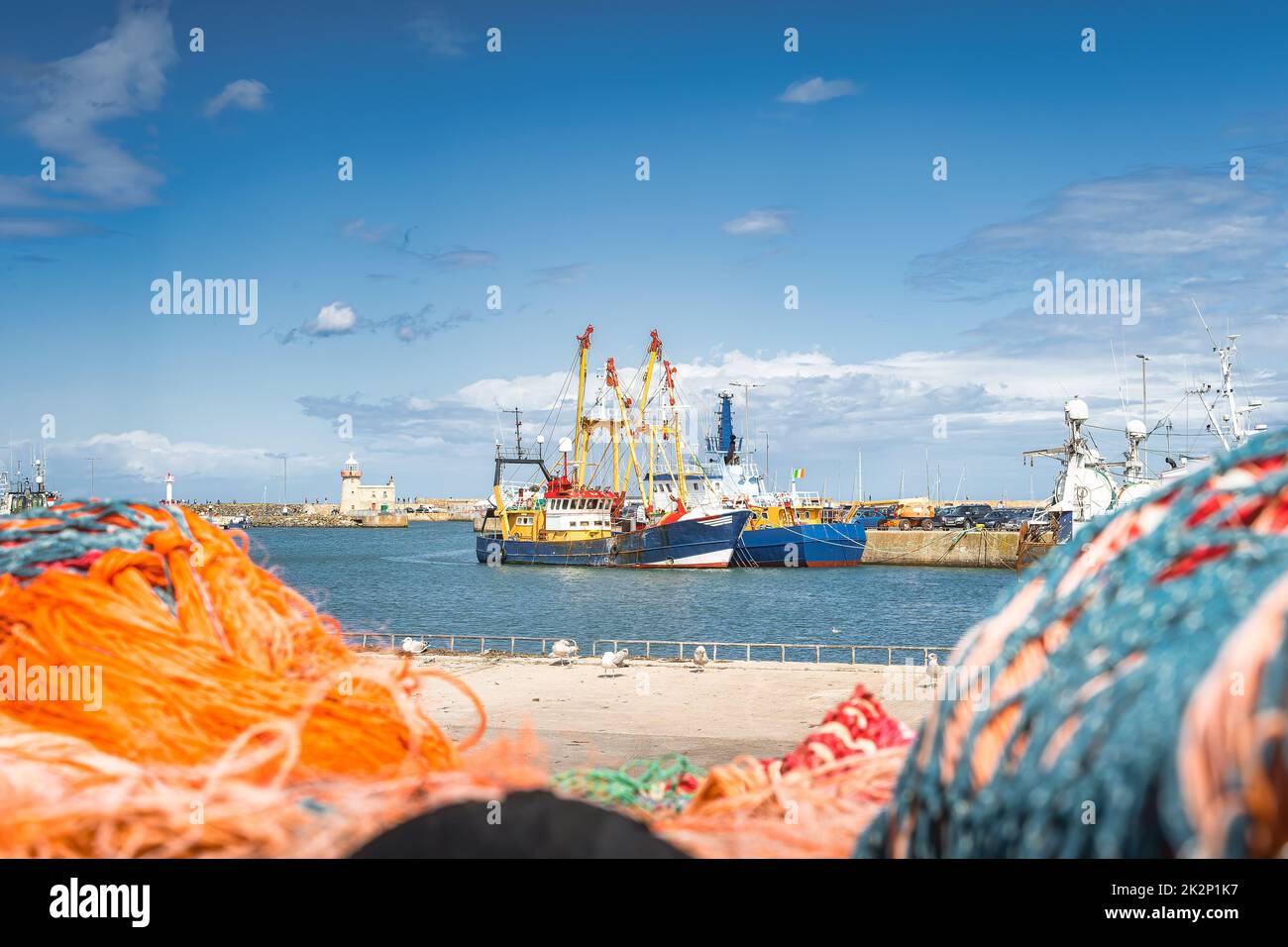 Large fishing boats moored in Howth harbour seen through blurred nets Stock Photo