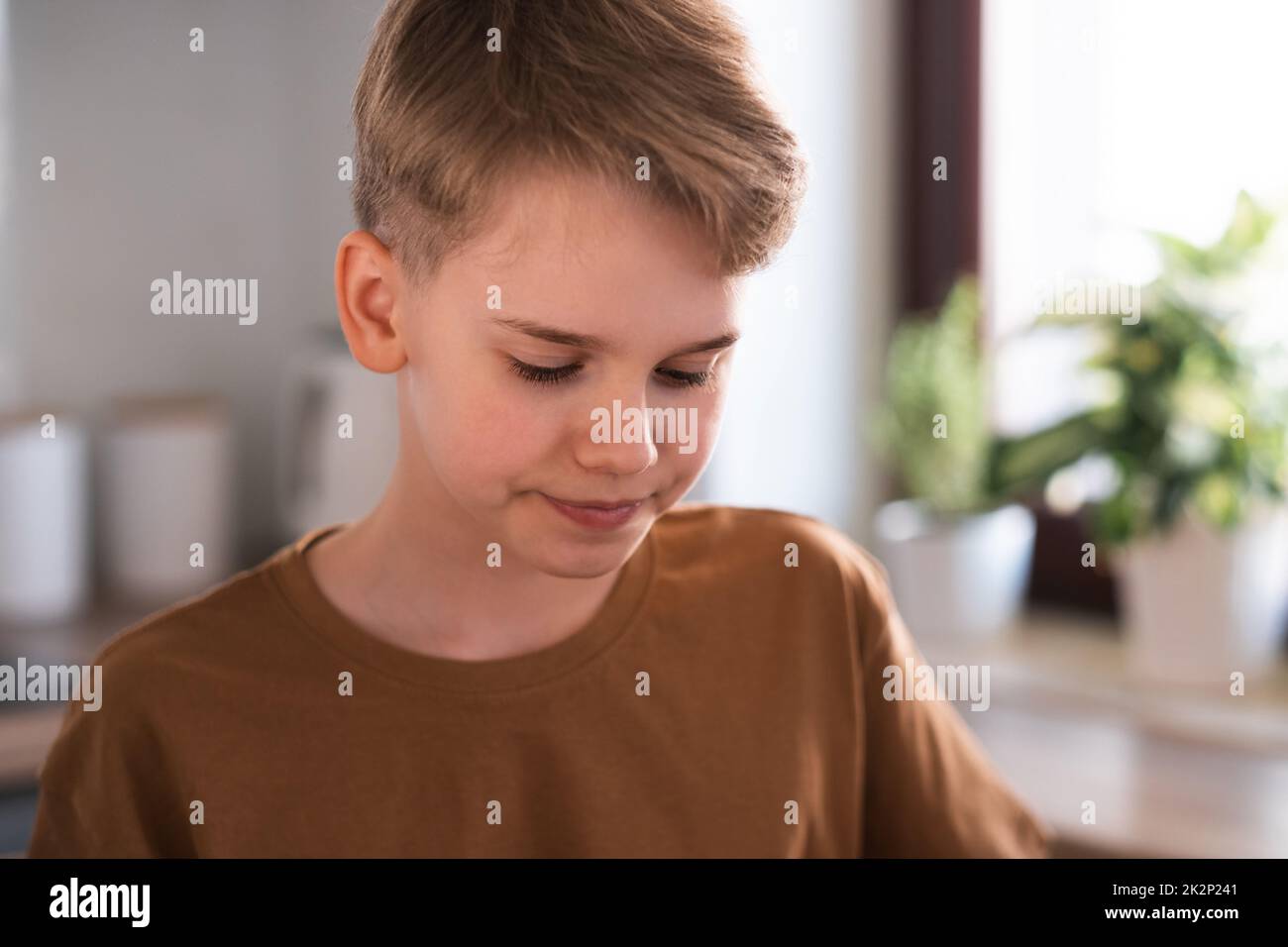 Close-up portrait of a cute blond teenager sitting in the kitchen Stock Photo