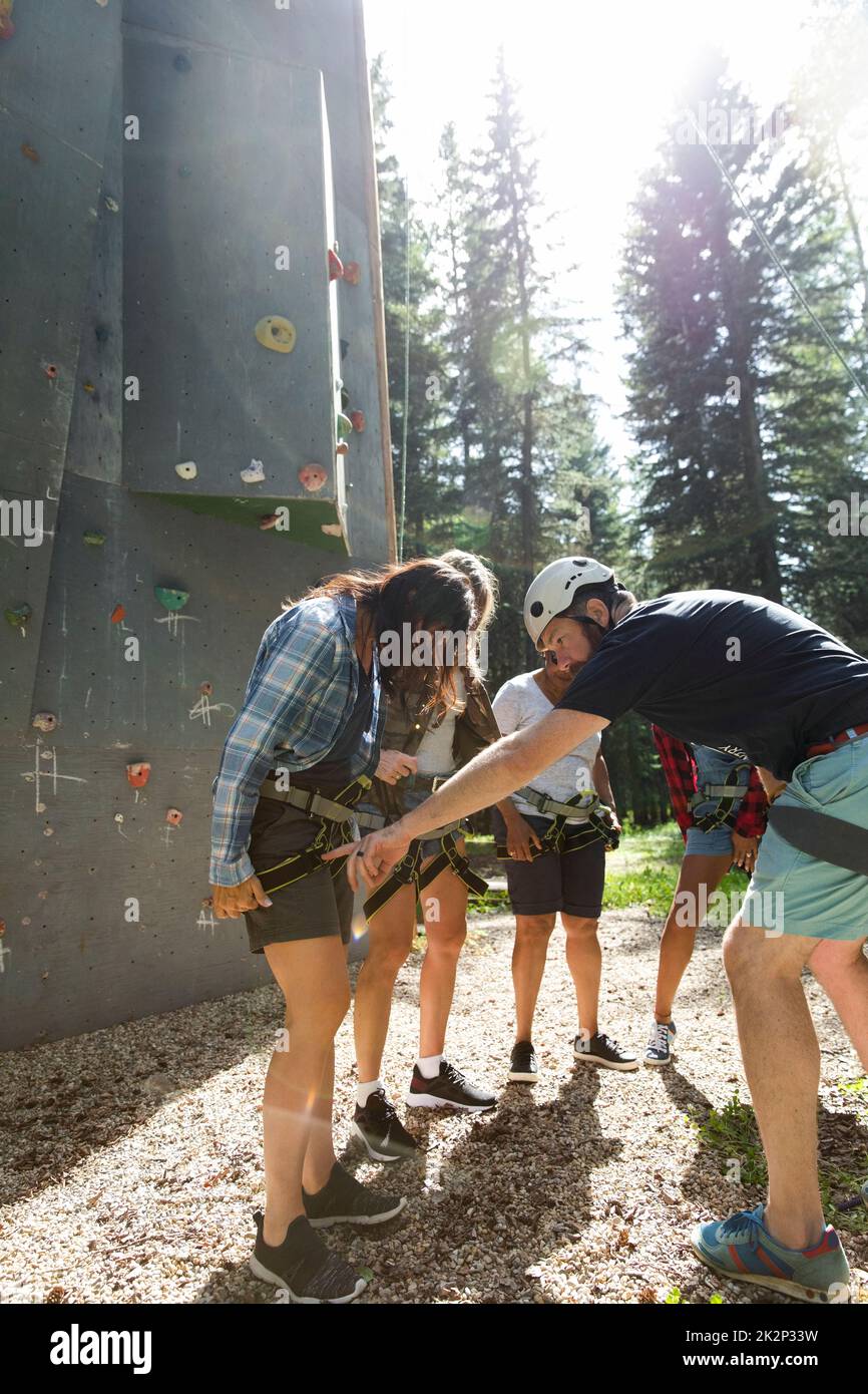 Instructor showing women how to use climbing harness Stock Photo Alamy