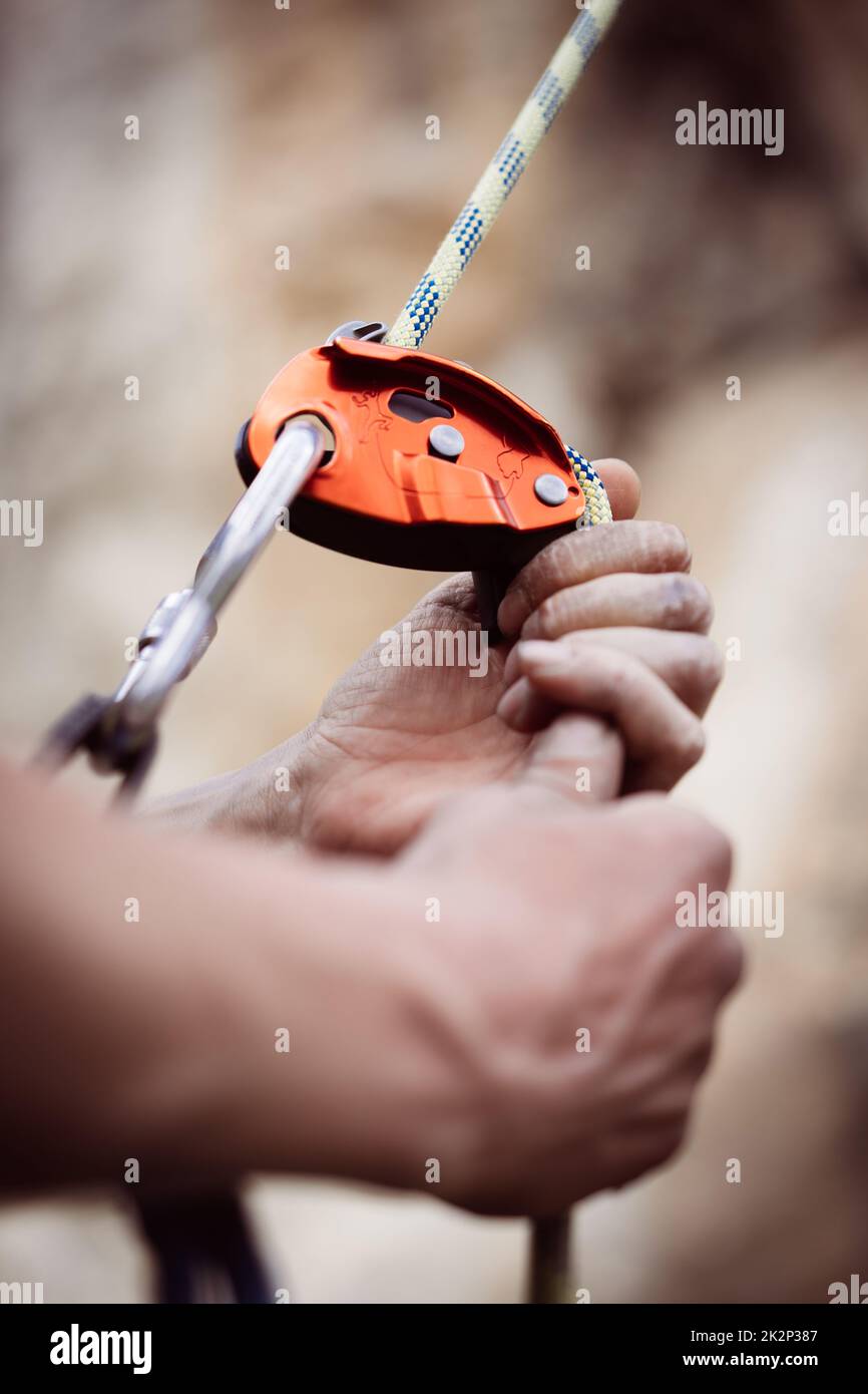 Man's hands operating a rock climbing belaying device Stock Photo