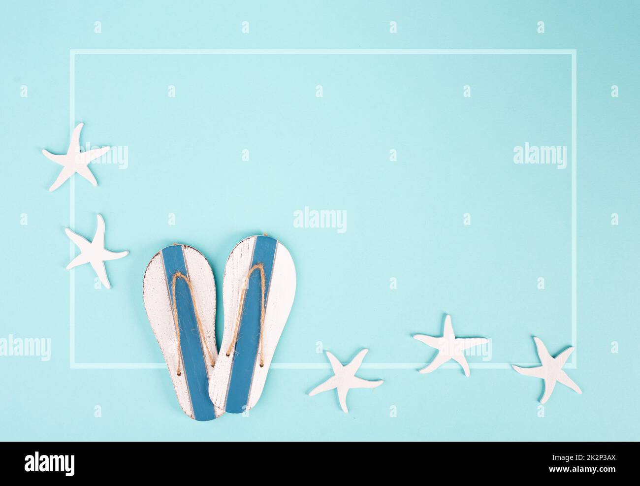 Blue colored summer and vacation background, slippers and sea stars building a frame, copy space for text, holiday and tourism concept Stock Photo