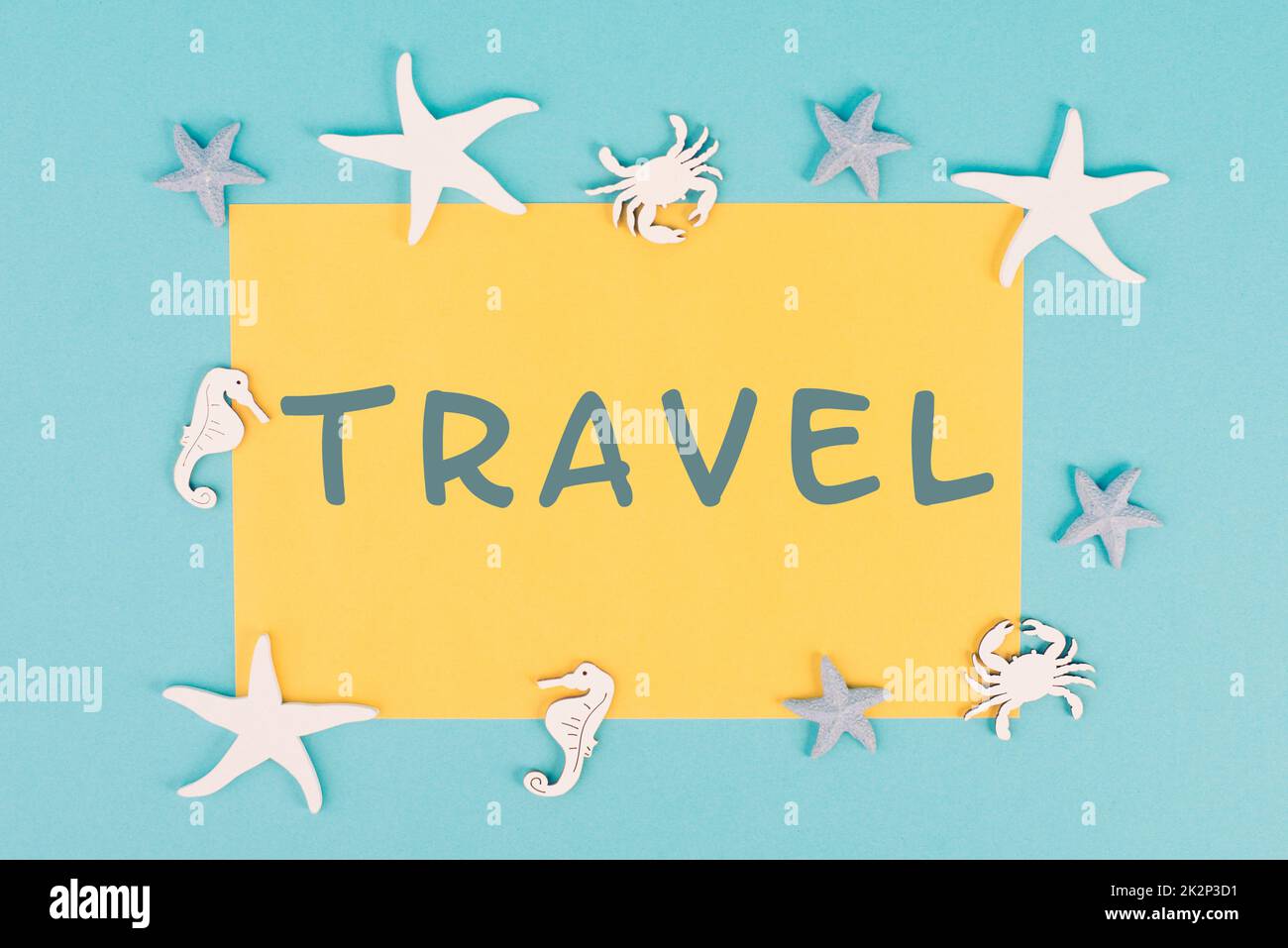 The word travel is standing on a yellow colored paper, sea stars, seahorses and crab bulding a frame, summer vacation, tourism destination Stock Photo