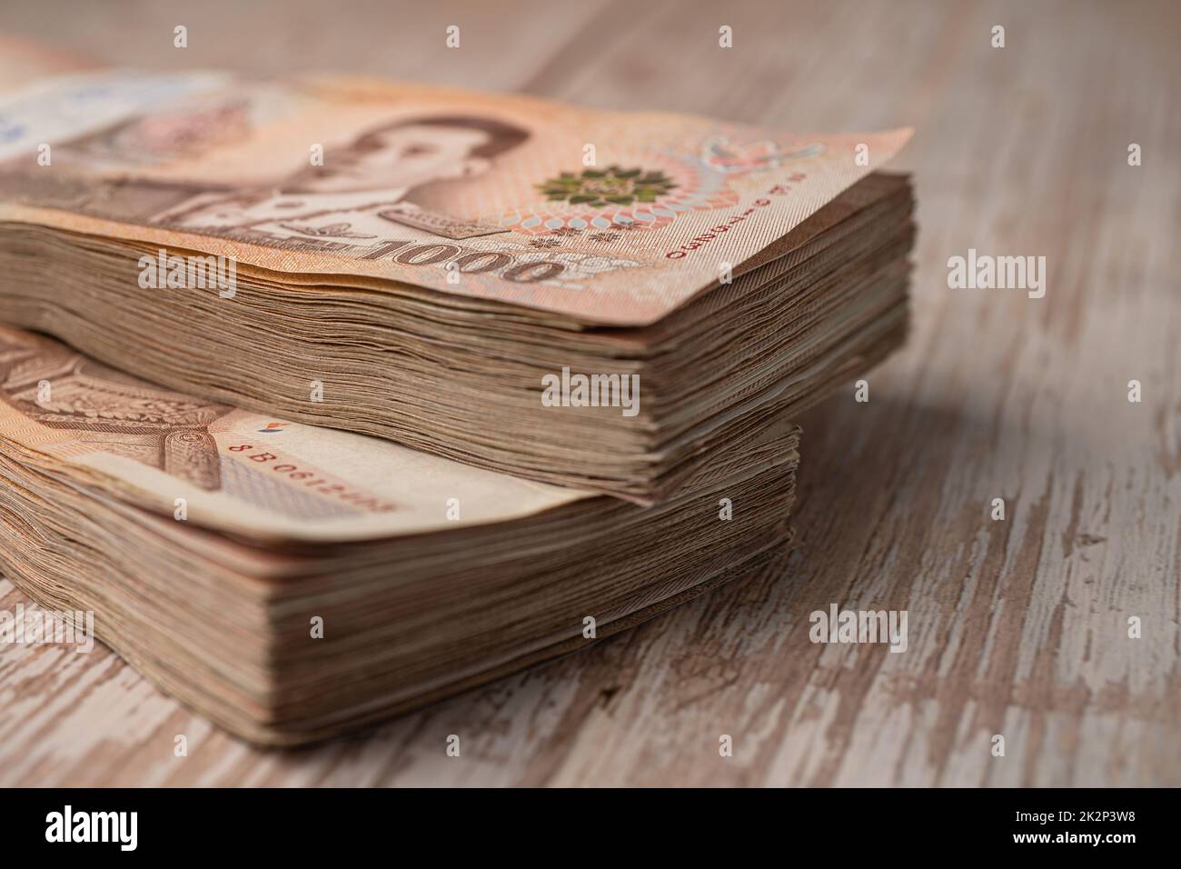 Stack of Thai baht banknotes on wooden background, business saving finance investment concept. Stock Photo