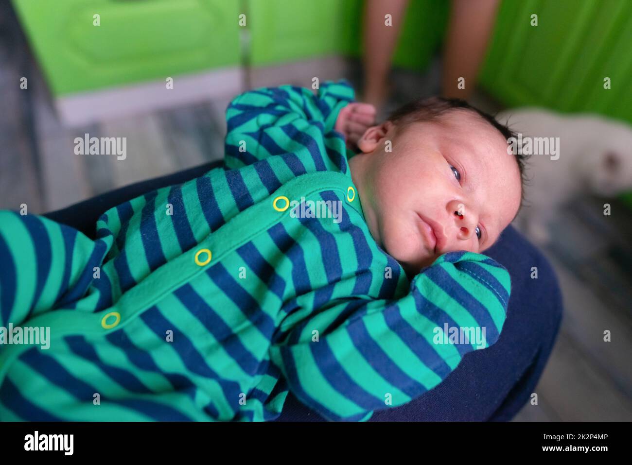 Infant baby in striped clothes lies with arms raised up Stock Photo Alamy