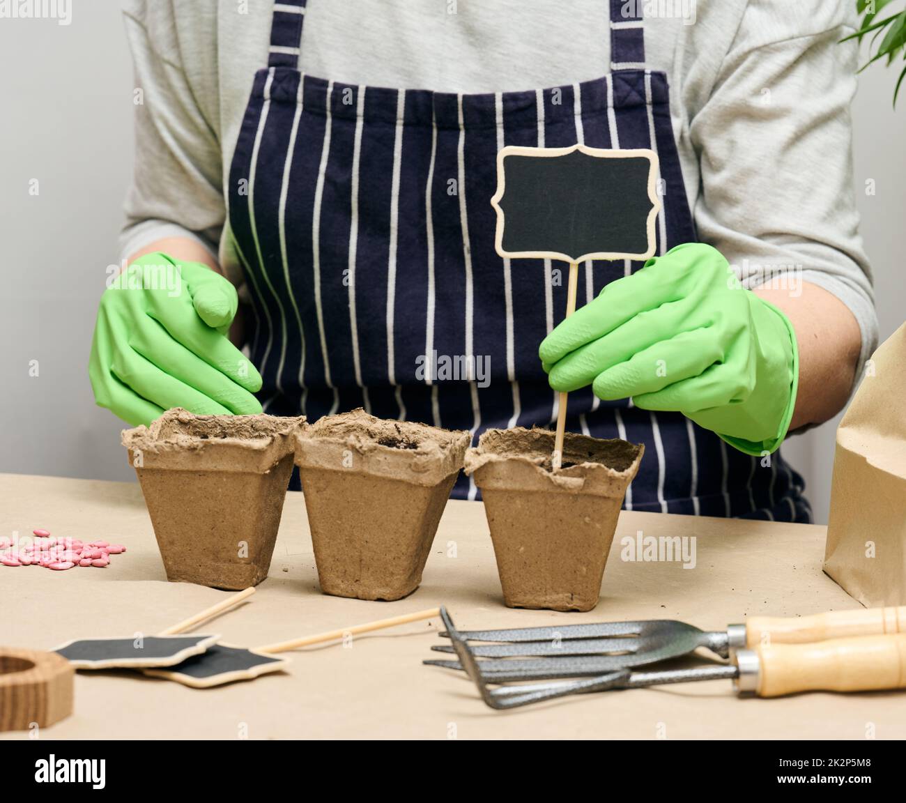 A woman arranges wooden markers in paper cups with soil to sign the ...
