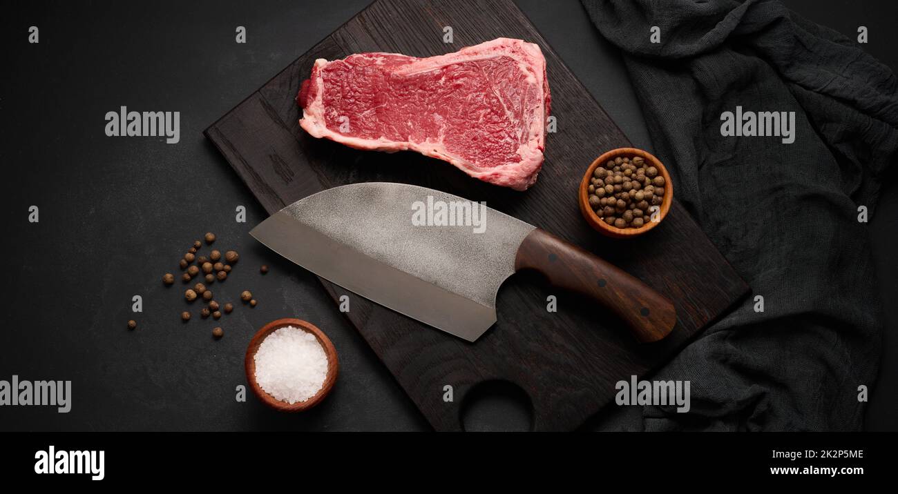 Fresh raw piece of beef meat, striploin steak on a black background, top view. Marbled piece of meat Stock Photo