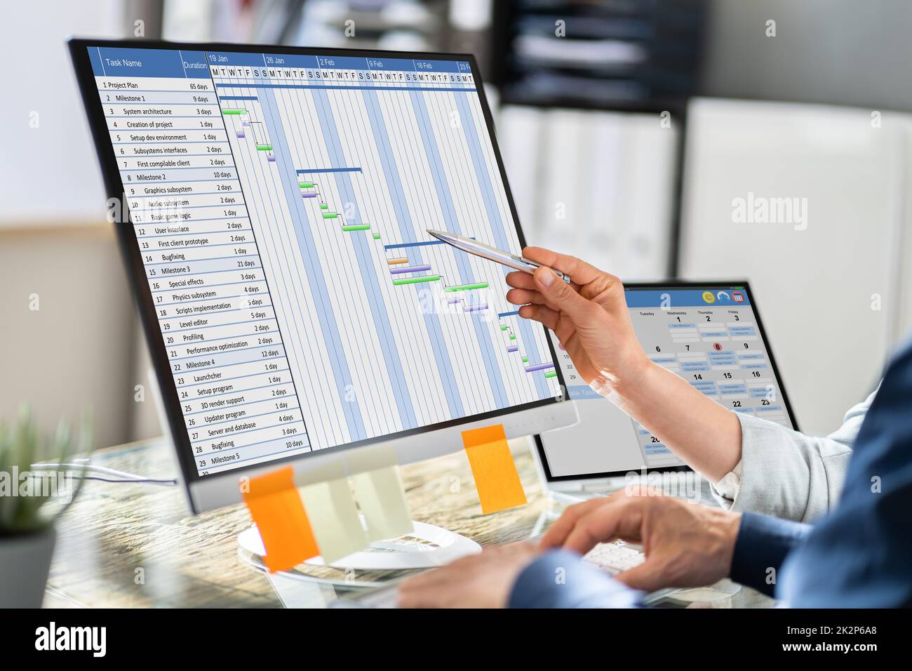 Businesspeople Analyzing Gantt Chart And Calendar On Computer Stock Photo