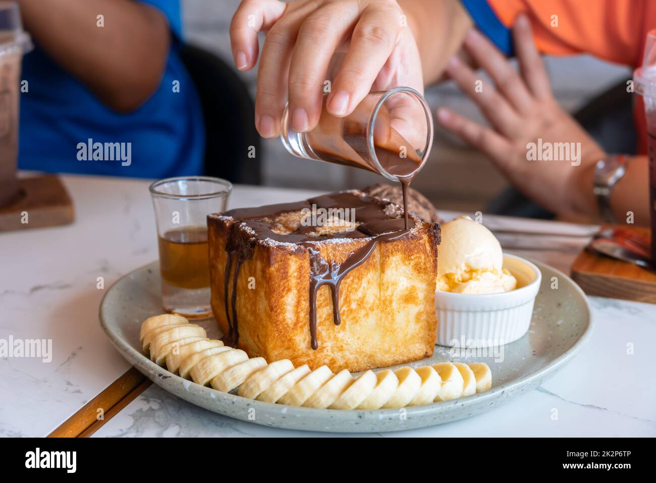 Honey toast served with banana slices, vanilla and chocolate ice cream on light green ceramic plate. Stock Photo