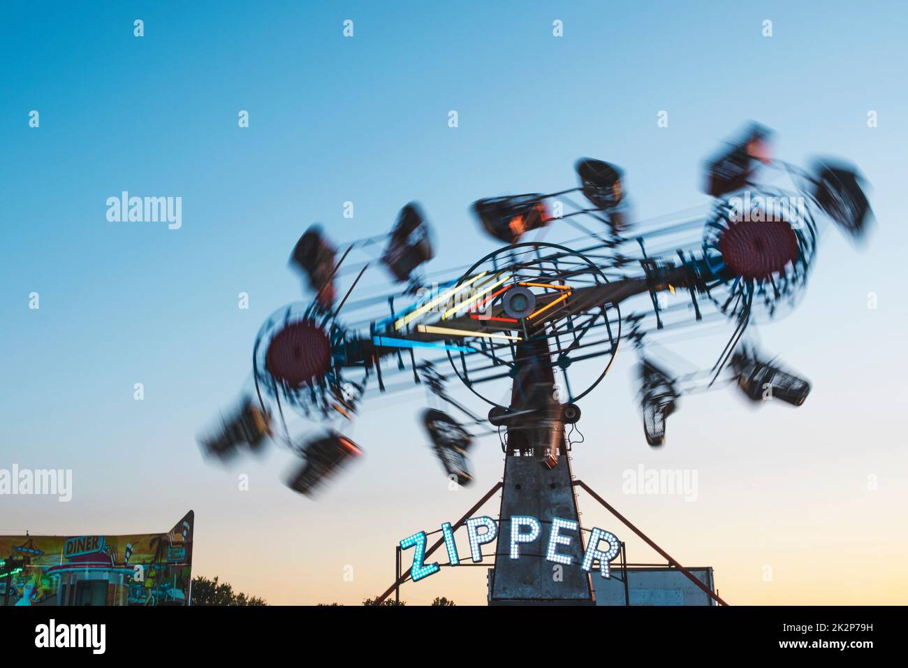 A zipper ride in background of blue sky in Decatur during sunset Stock Photo