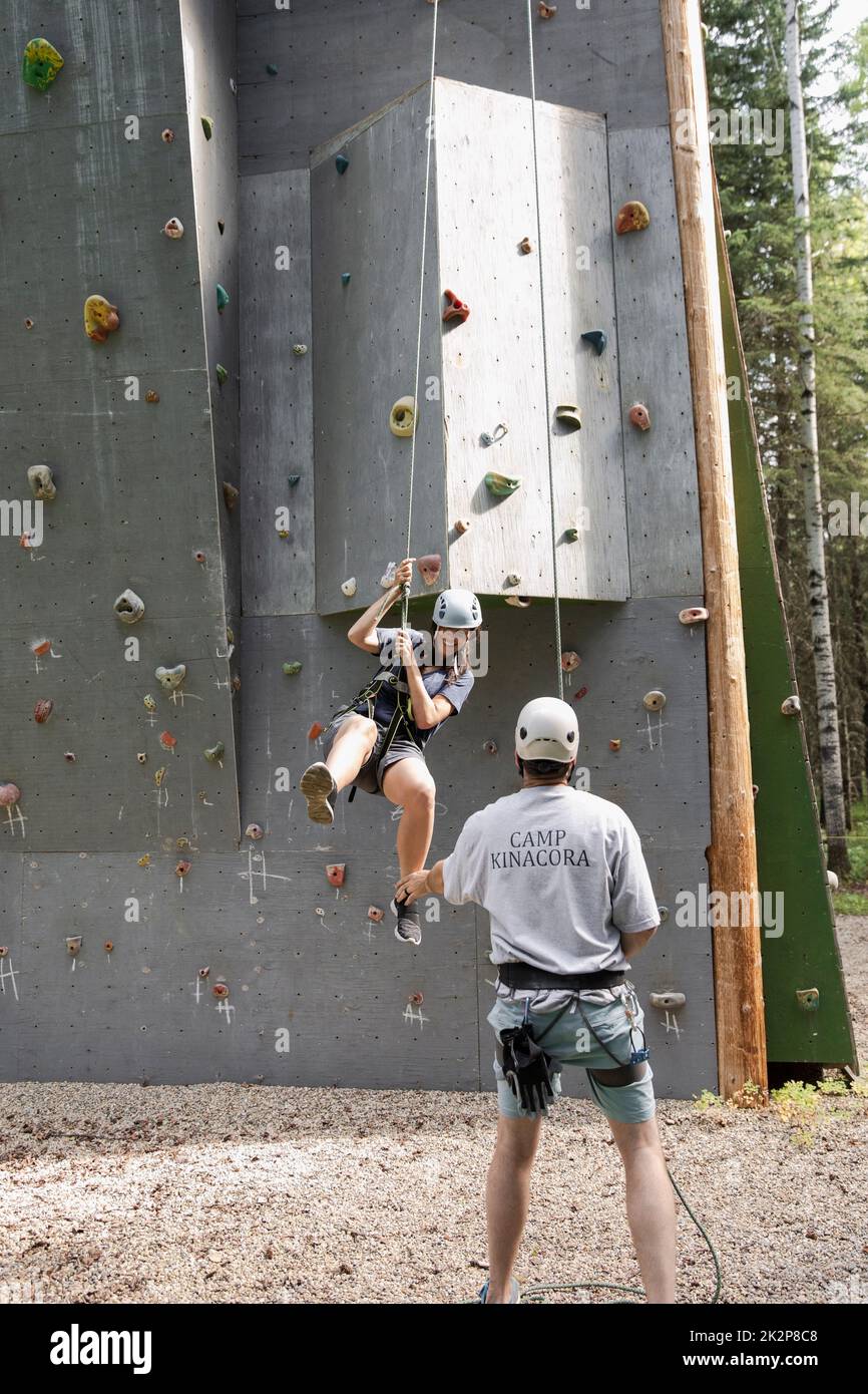 Woman swinging from climbing wall in forest Stock Photo Alamy