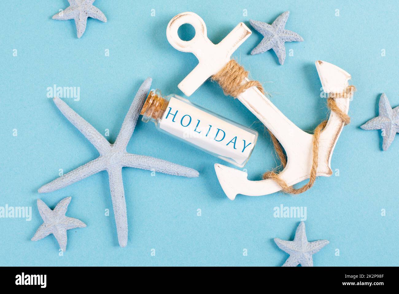 Blue colored summer and vacation background, anchor, sea stars and a glass bootle with the word holiday, travel and tourism concept Stock Photo