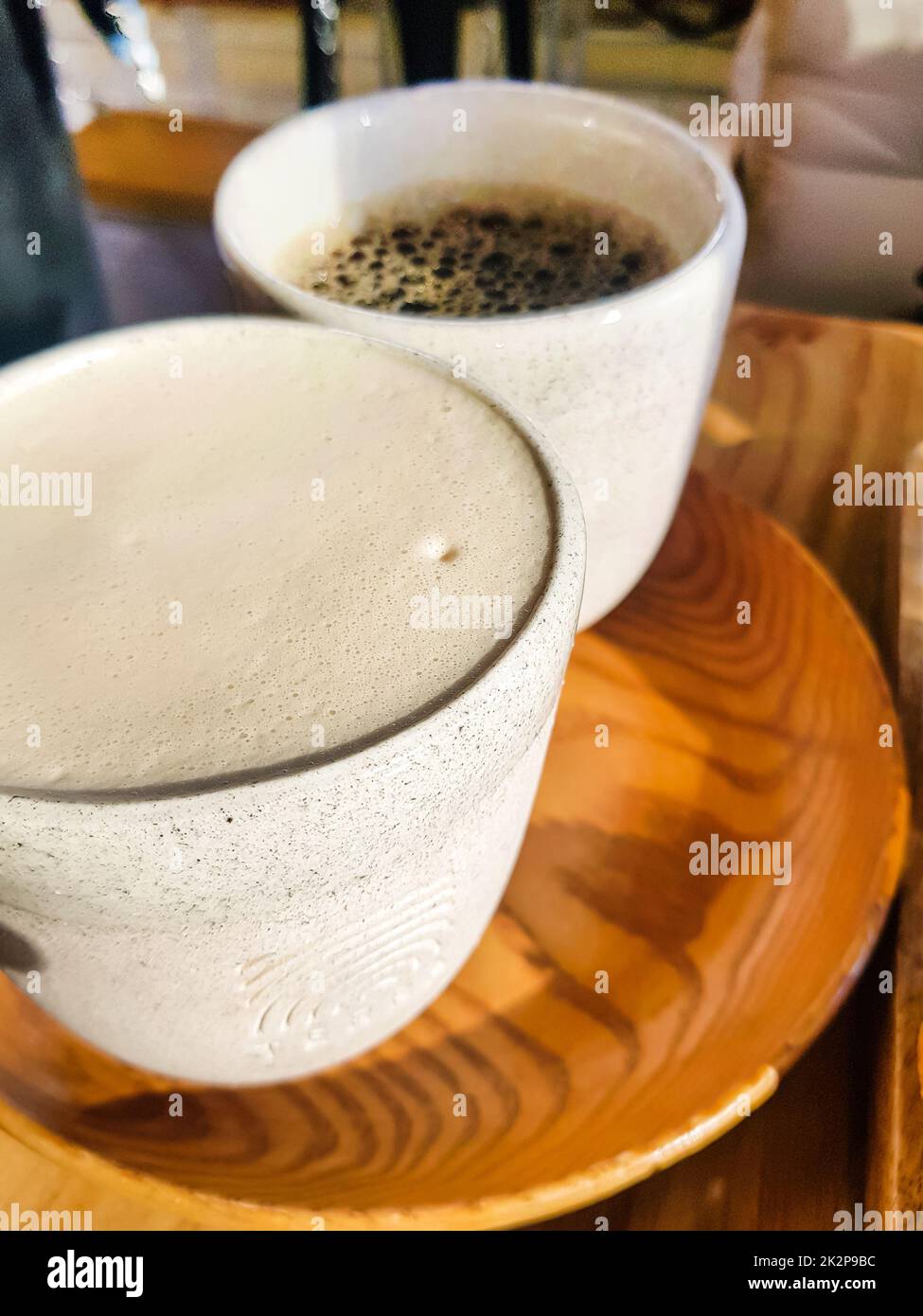 Cappuccino with fragrant milk foam and black Americano on a wooden tray. View from above. Coffee for two. Delicious freshly brewed coffee for breakfast in the cafe Stock Photo