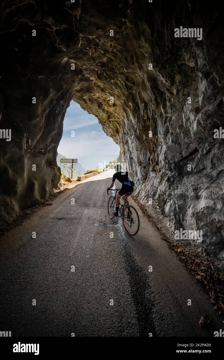 Male road cyclist riding through a tunnel on the balcony road to Villard Notre Dame from Bourg d'Oisans, French Alps. Stock Photo