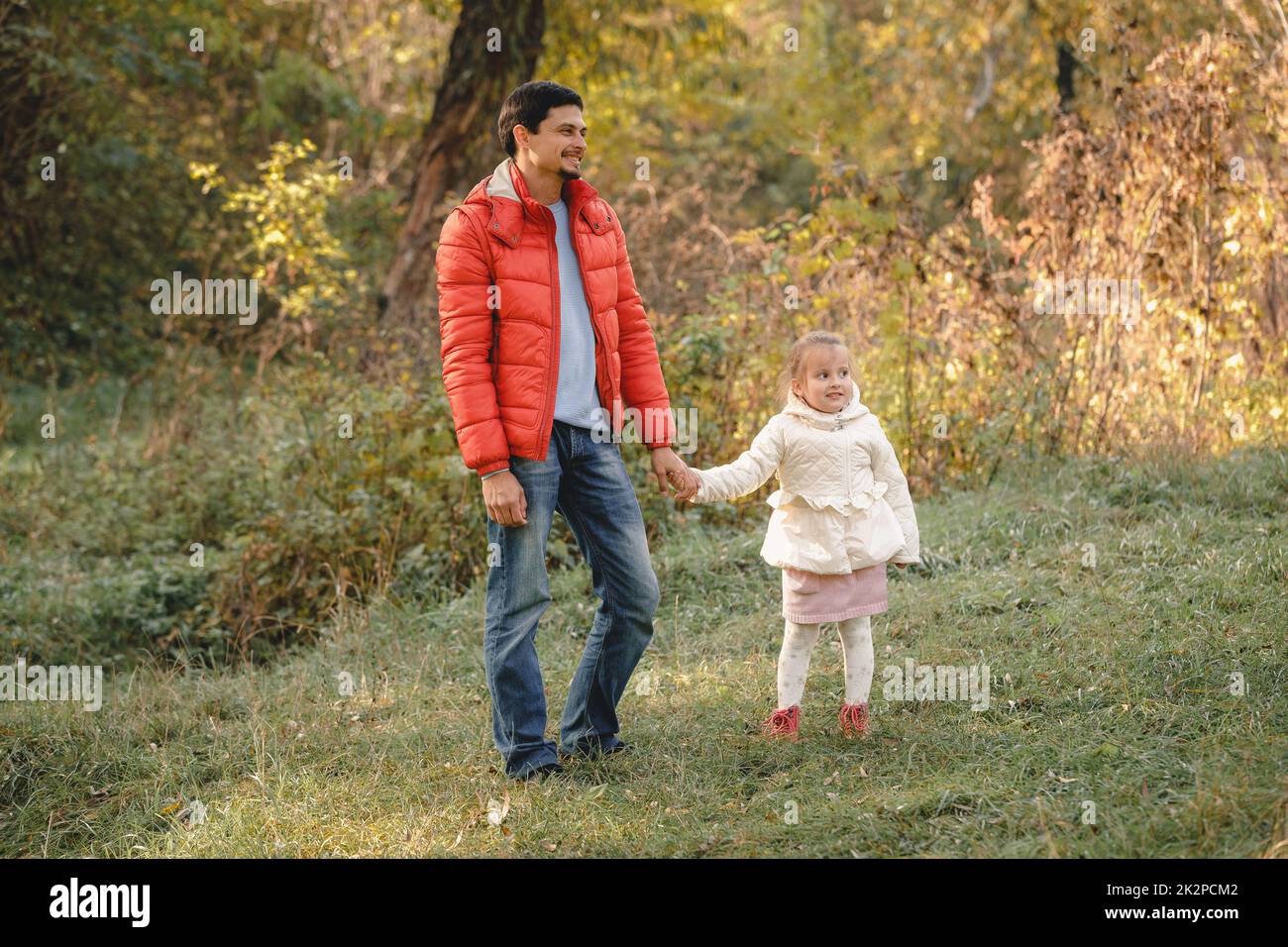 father walks with little daughter girl and smiles happily Stock Photo