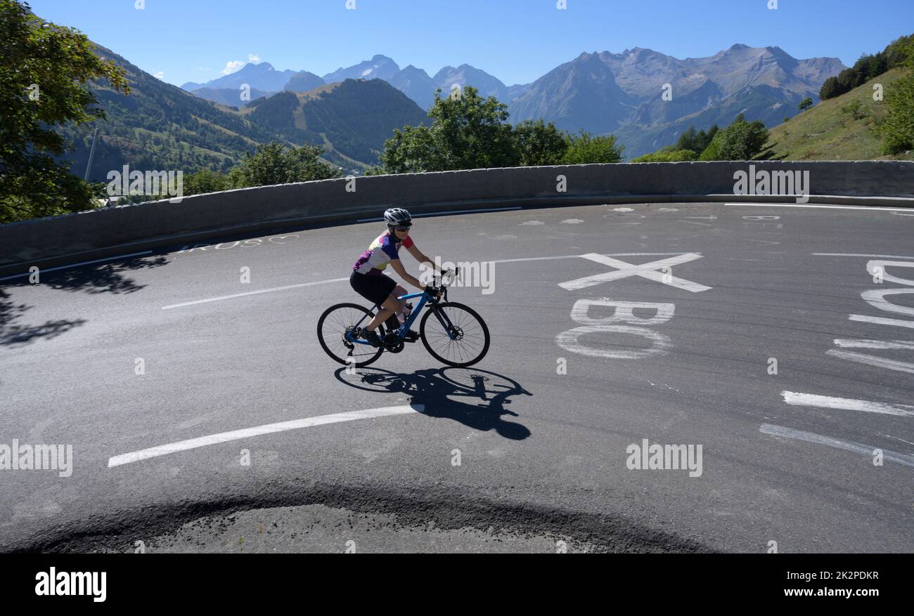 Mature female road cyclist riding through the famous bend 3 on the Tour de France climb of Alpe d'Huez. Stock Photo