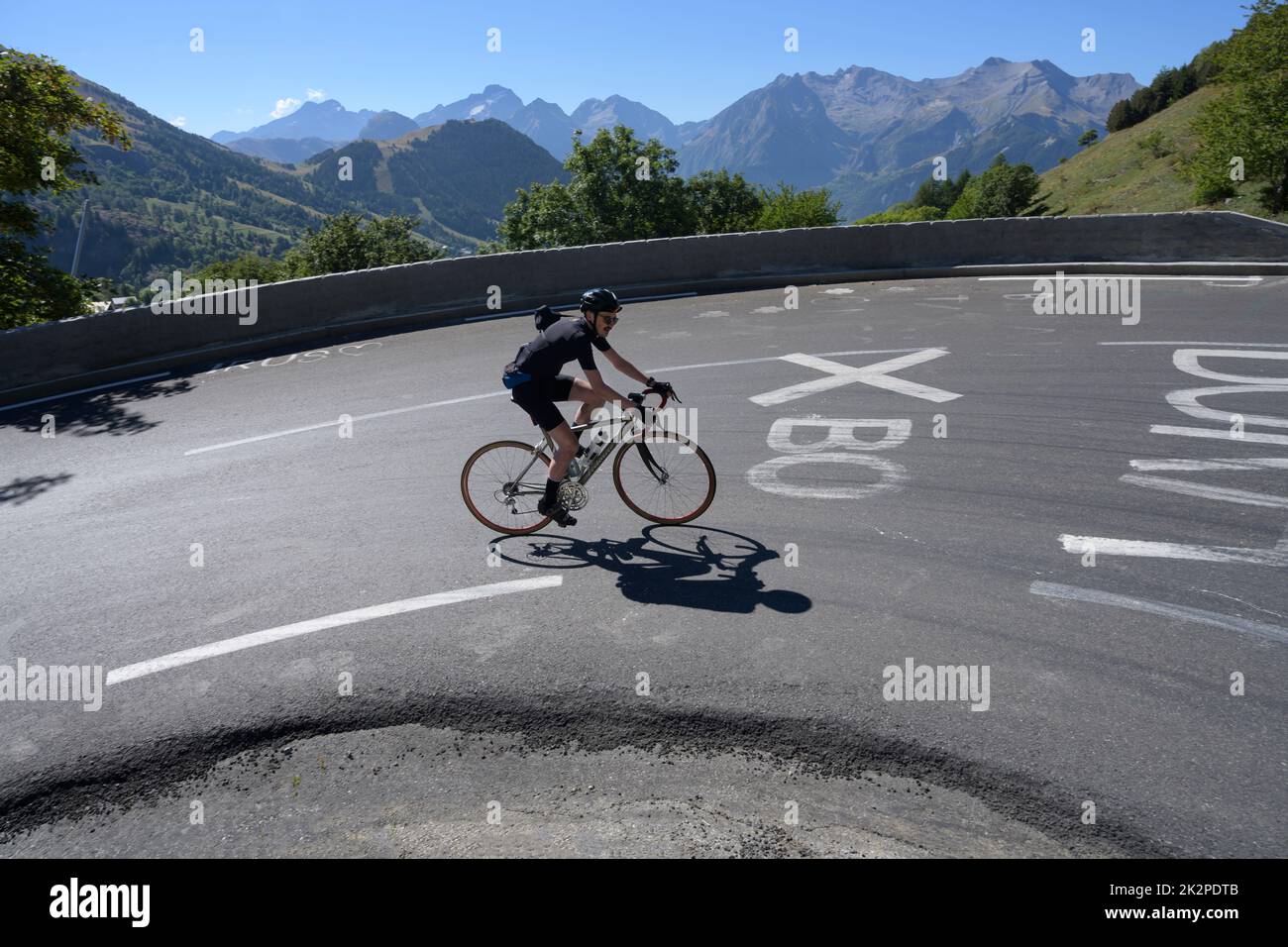 Male road cyclist riding through the famous bend 3 on the Tour de France climb of Alpe d'Huez. Stock Photo
