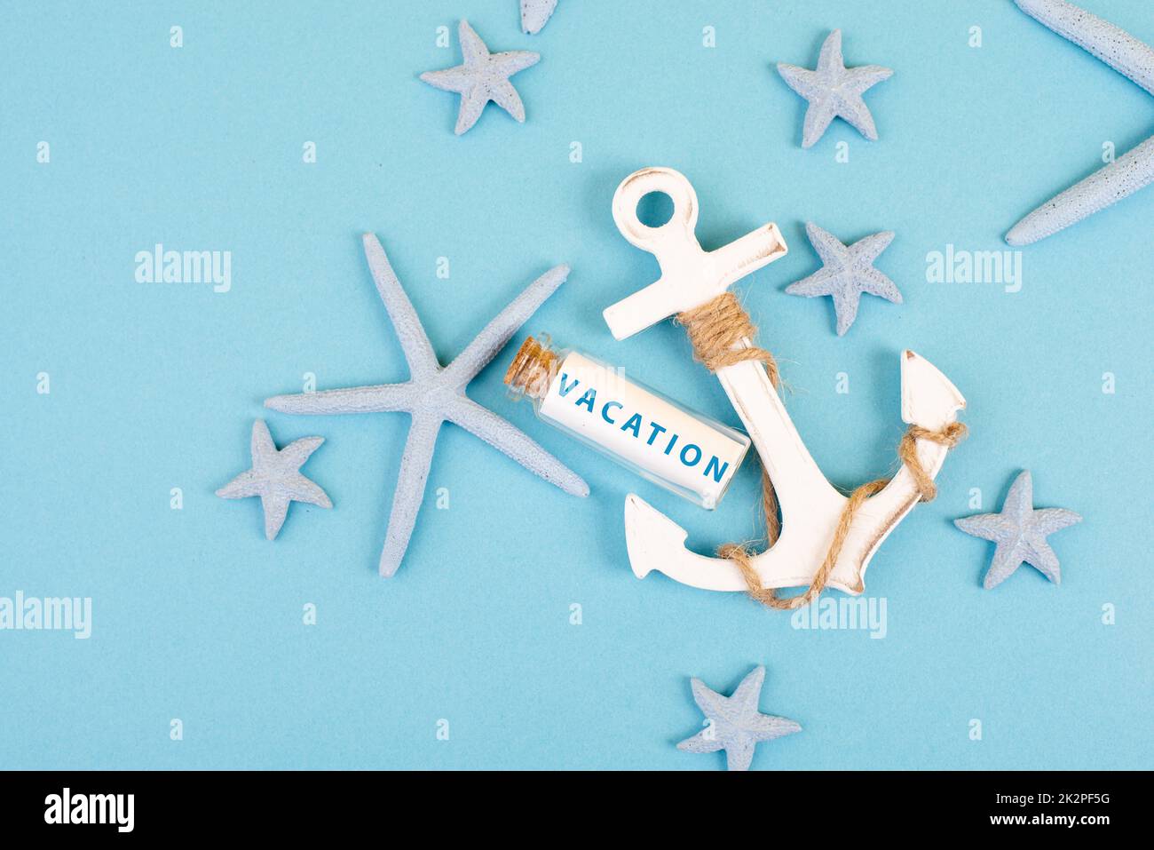 Blue colored summer and holiday background, anchor, sea stars and a glass bootle with the word vacation, travel and tourism concept Stock Photo
