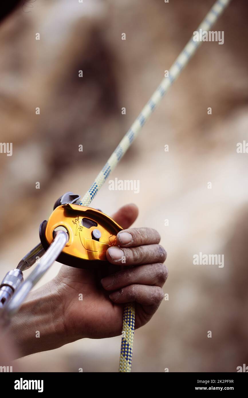 Close up shot of a man's hands operating a rock climbing assisted belaying device. Stock Photo