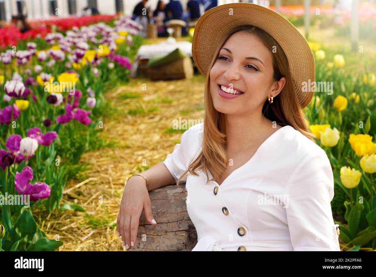 Smiling girl sitting relaxed between tulips fields on springtime