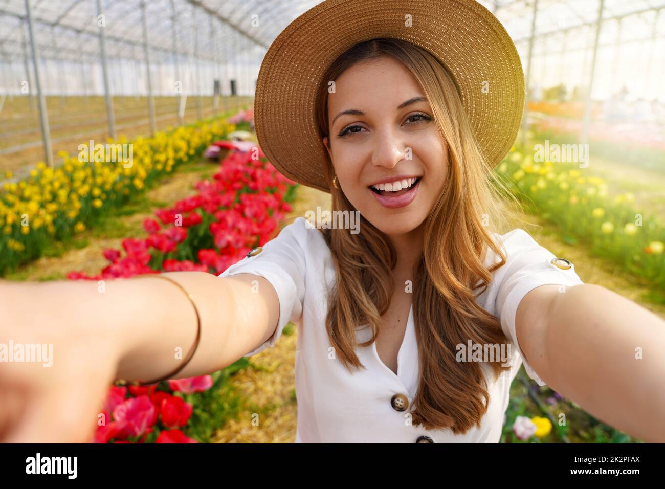 Cheerful happy young hispanic woman in greenhouse take selfie by camera on springtime Stock Photo