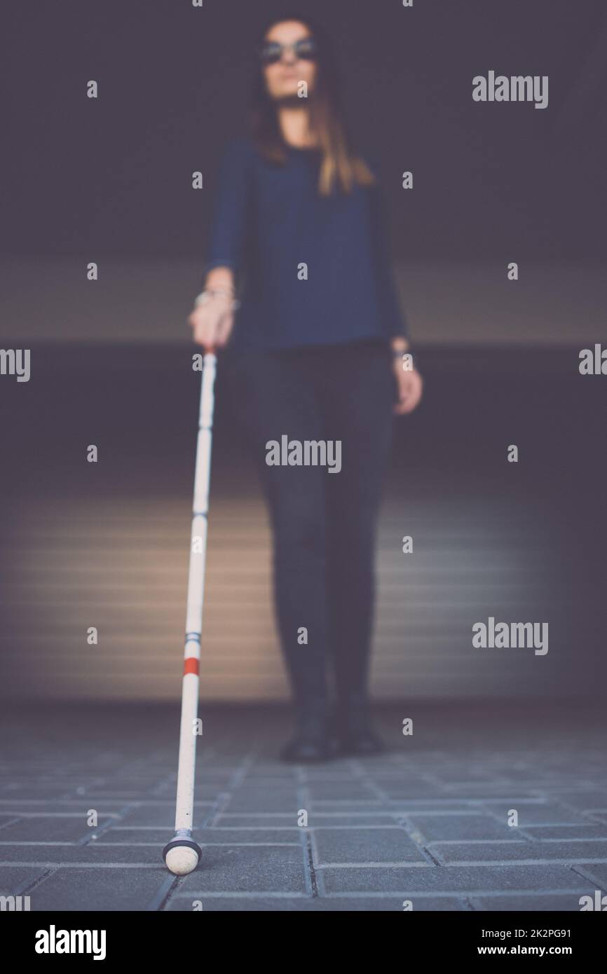 Young woman with impaired vision walking on city streets, using her