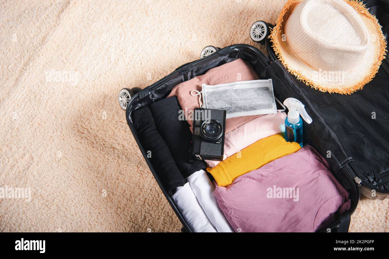 Open suitcase with traveler belongings clothes and accessories of things ready packing to be taken on summer holiday Stock Photo