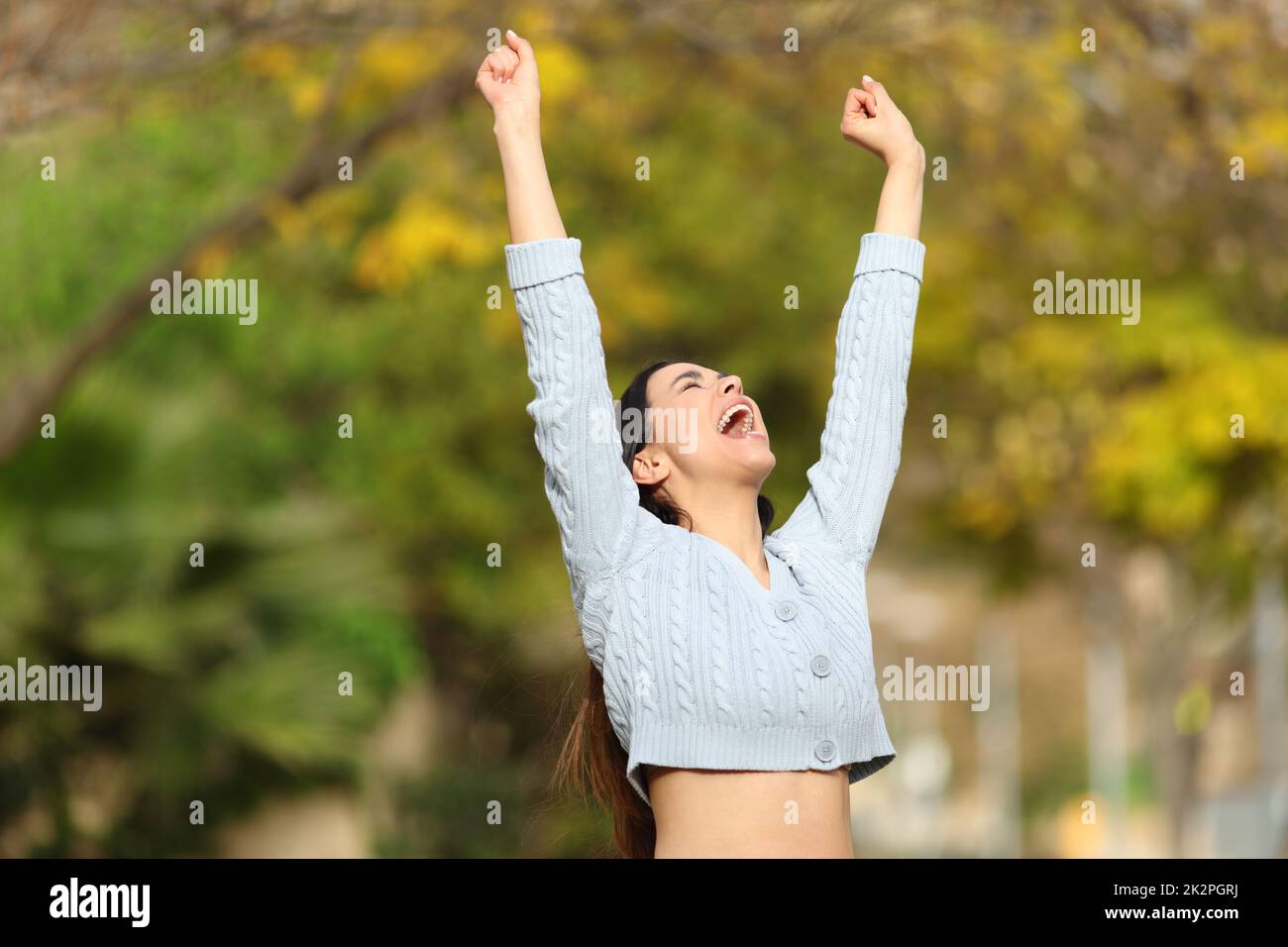 Excited woman raising arms in a park celebrating good day Stock Photo ...