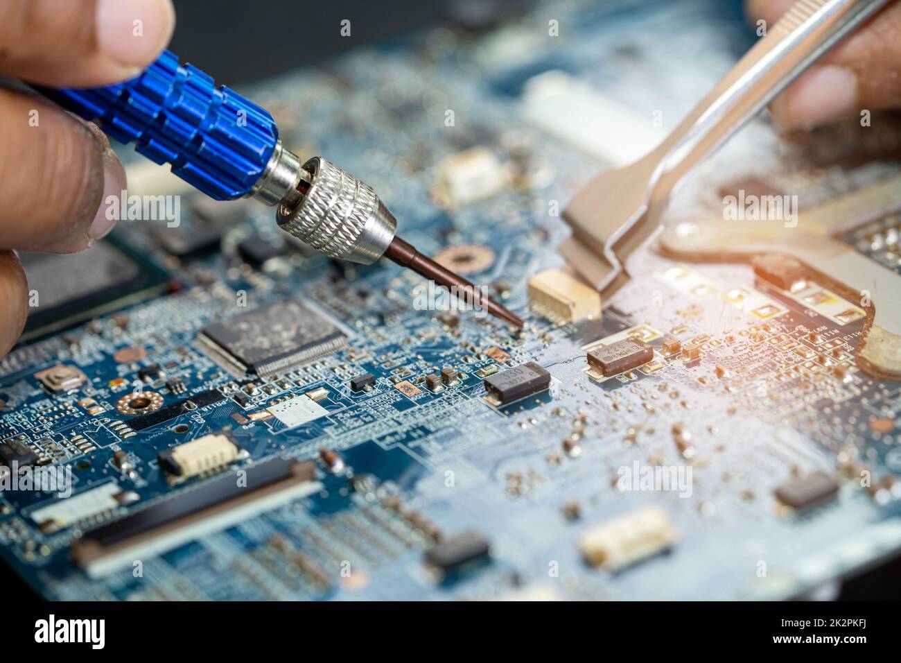 Technician repairing inside of printed circuit board PCB by soldering iron. Integrated Circuit. the concept of data, hardware, technician and technology. Stock Photo