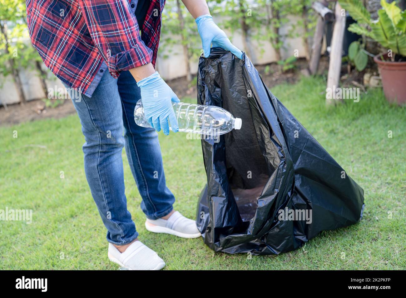 Asian woman volunteer carry water plastic bottles into garbage bag trash in park, recycle waste environment ecology concept. Stock Photo