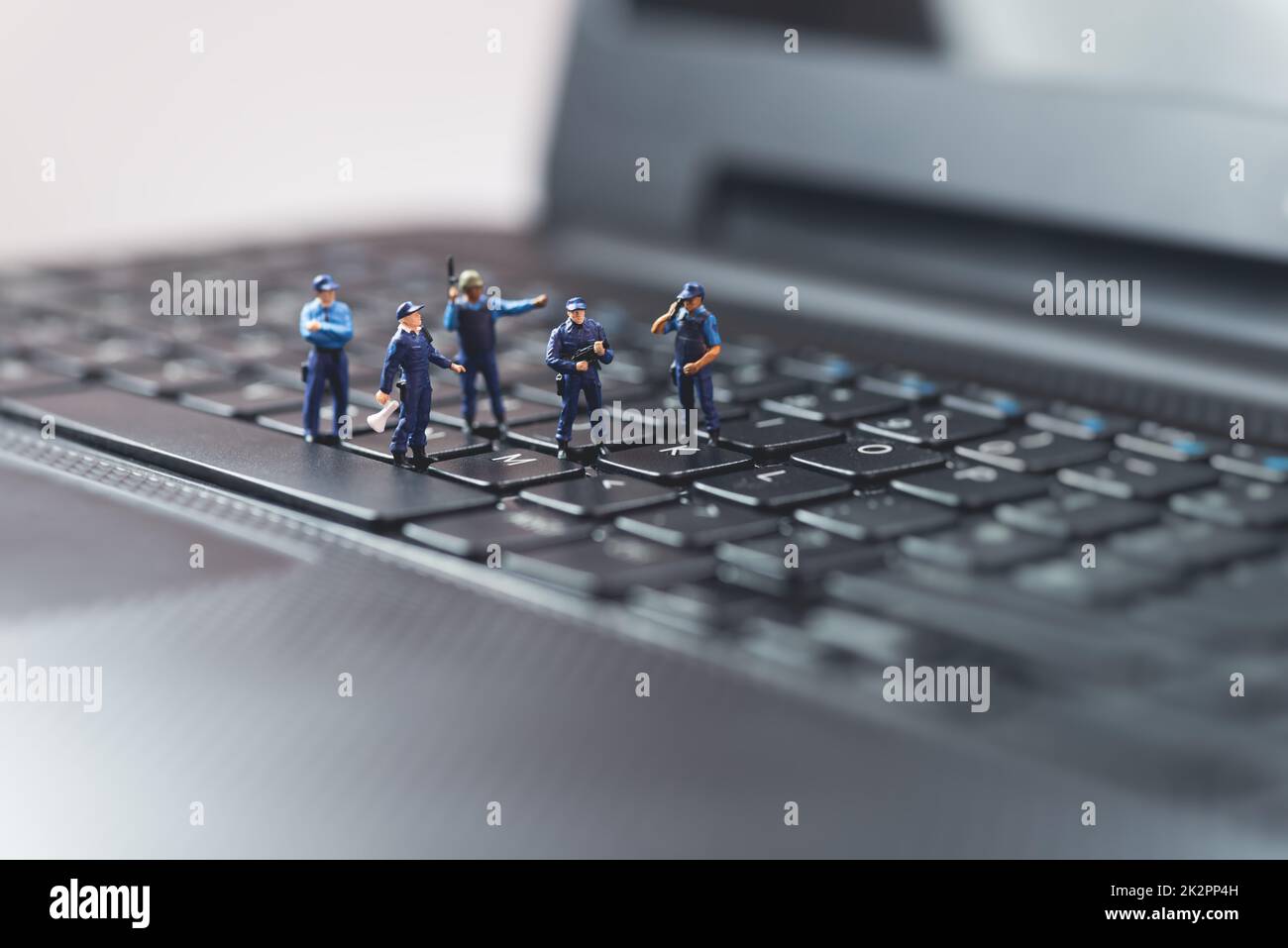 Miniature police squad protecting laptop computer. Technology concept ...