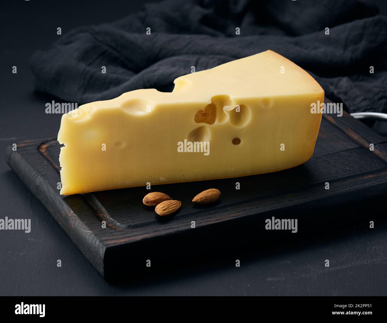 triangular piece of maasdam cheese on a brown wooden board Stock Photo ...