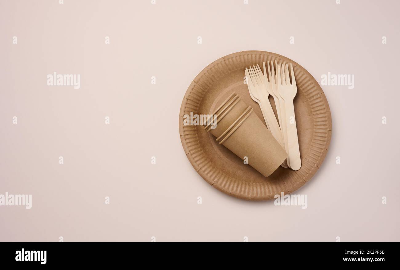 Brown paper cups and plates on a beige background. Recyclable garbage, rejection of plastic Stock Photo