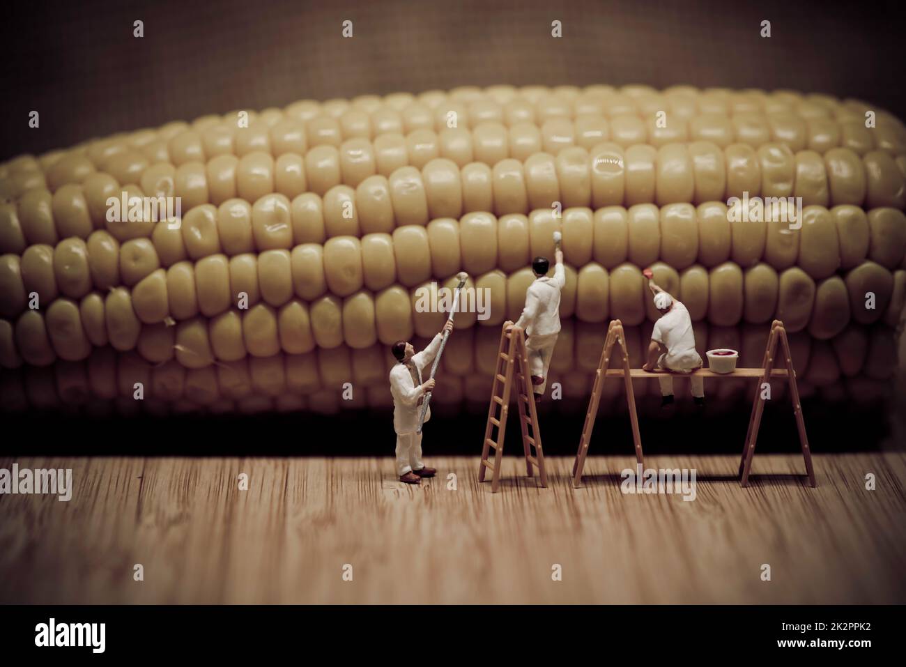 Miniature painters coloring corn on the cob Stock Photo
