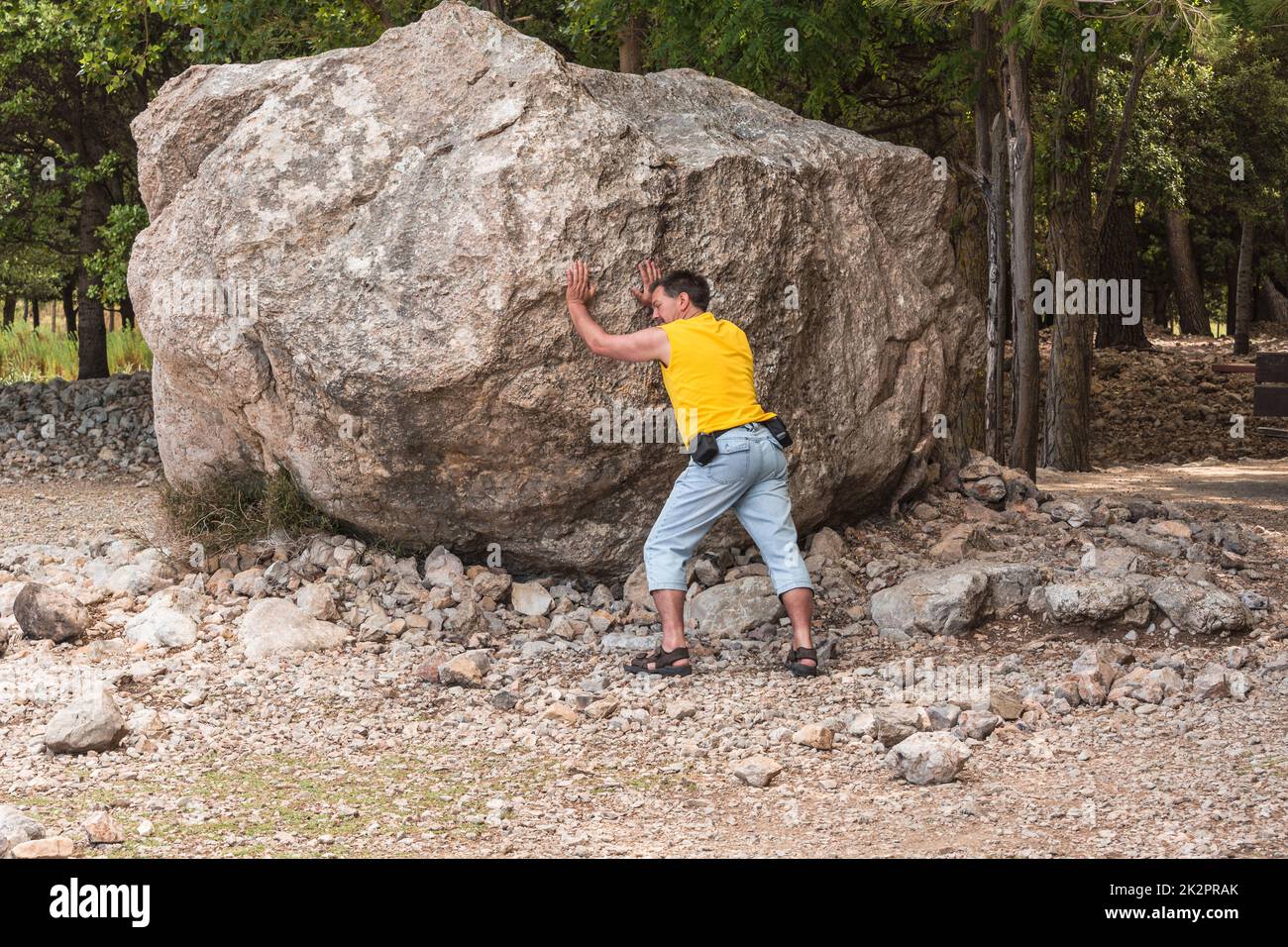 Man stands in front of a large rock. erratic boulder which was built by erosion. Stock Photo