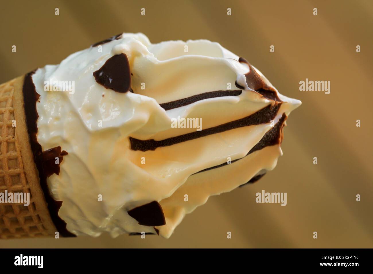 A close-up of a delicious ice cream cone with waffle, vanilla ice cream and chocolate icing. Stock Photo