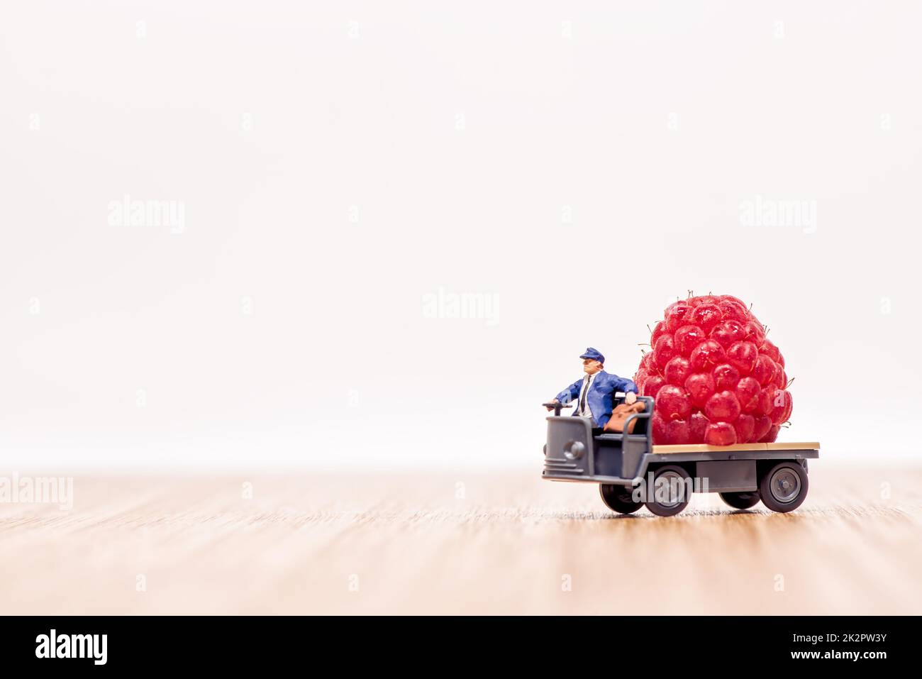 Miniature lorry loaded with giant raspberry. Fruit delivery concept Stock Photo