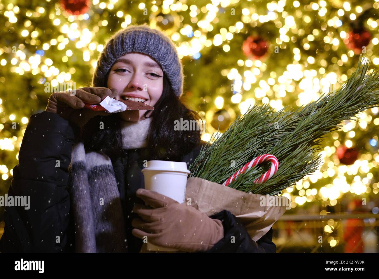 young beautiful happy Face of smiling girl posing. Christmas tree Happy New Year eating Chocolate with coffe cup Stock Photo