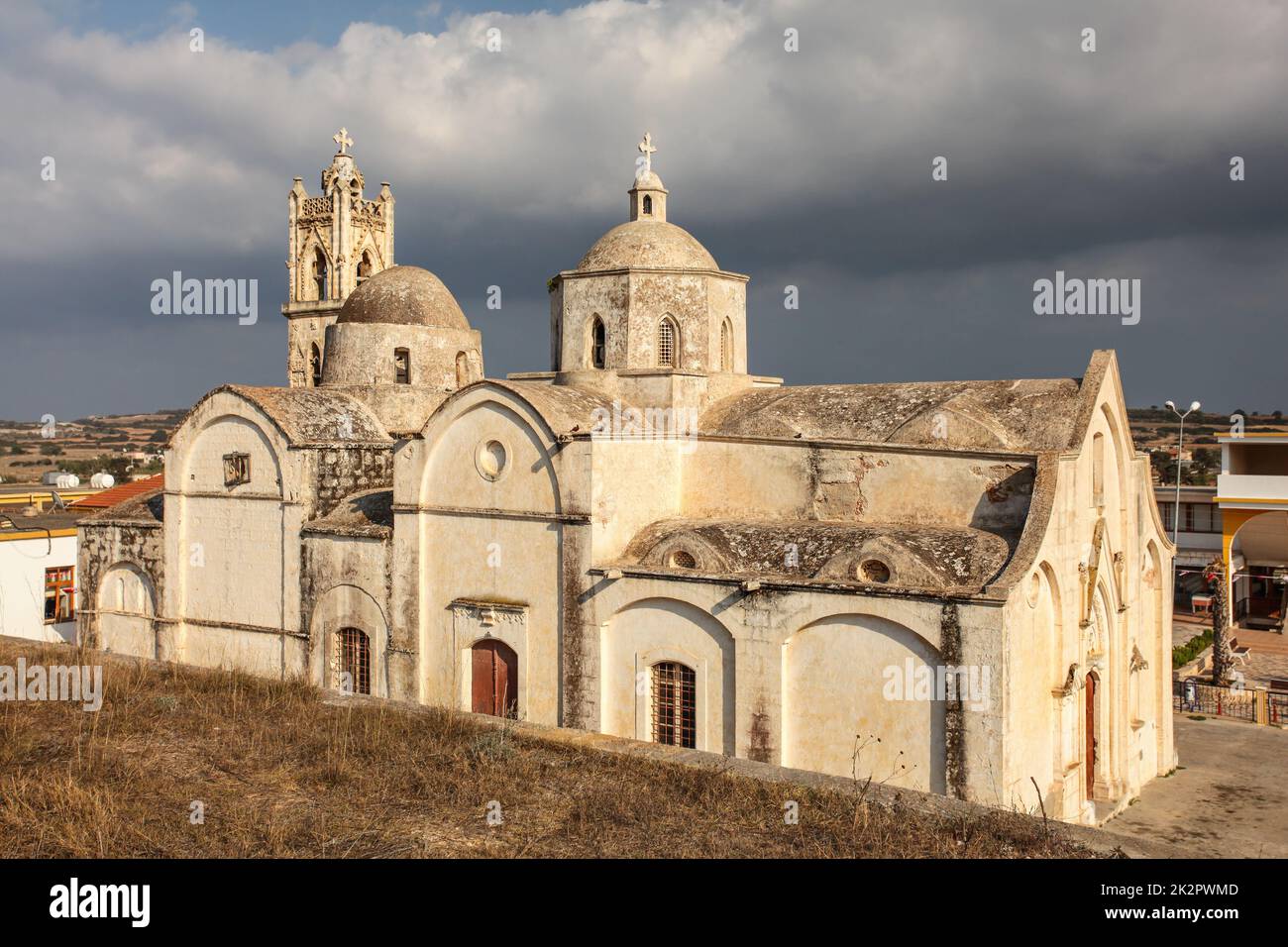 Ayios Synesios Church in Rizokarpaso (Dipkarpaz), lit by afternoon sun, some heavy clouds in background. This northern Cyprus town is known for Christians and Muslims living in harmony. Stock Photo