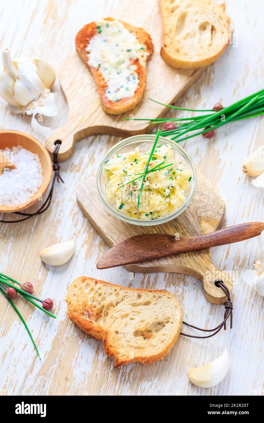 Homemade garlic butter with herbs and chives and fresh roasted baguette