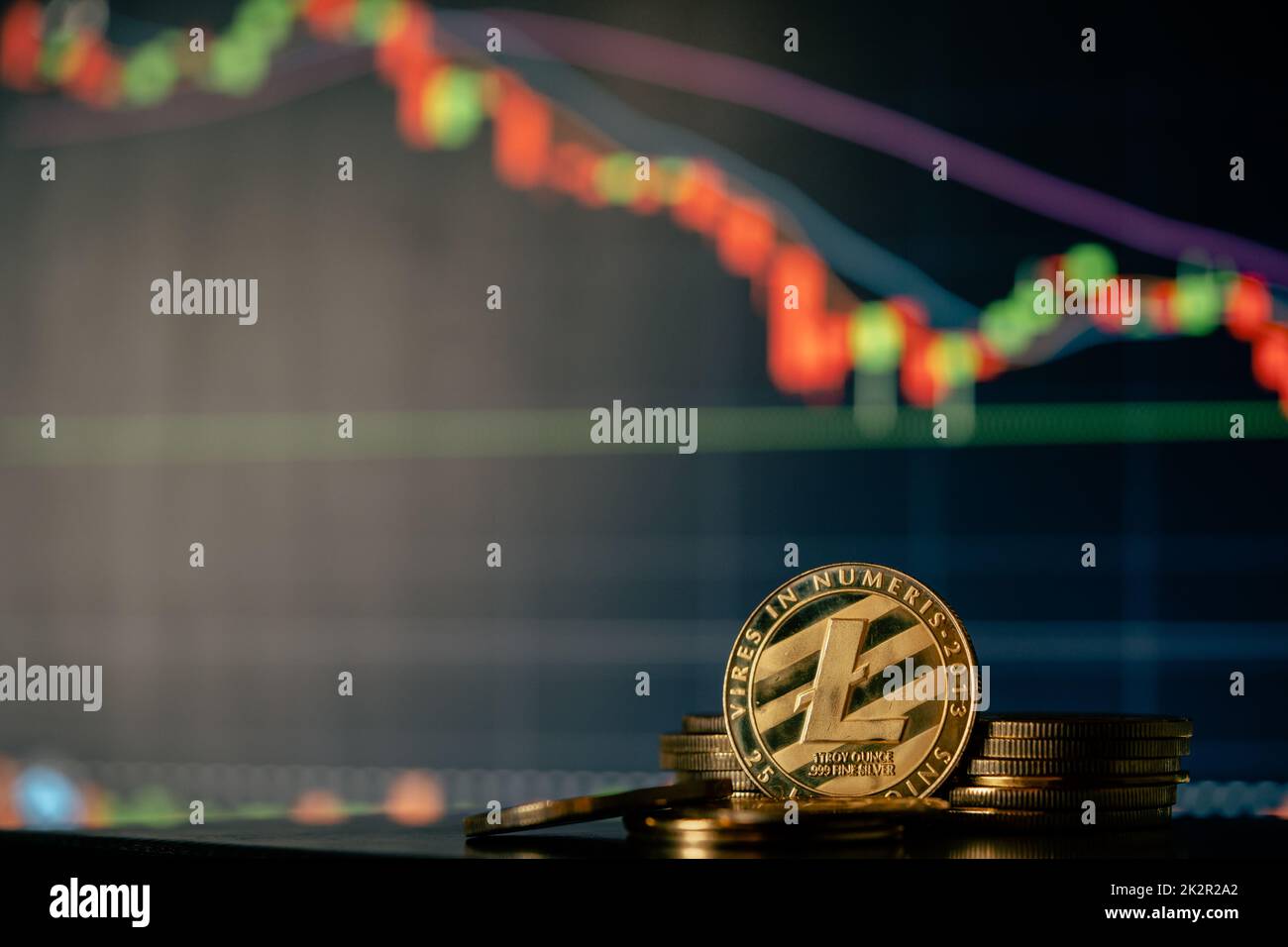 Stack or heap of gold Litecoin cryptocurrency with candle stick graph chart and digital background. Stock Photo