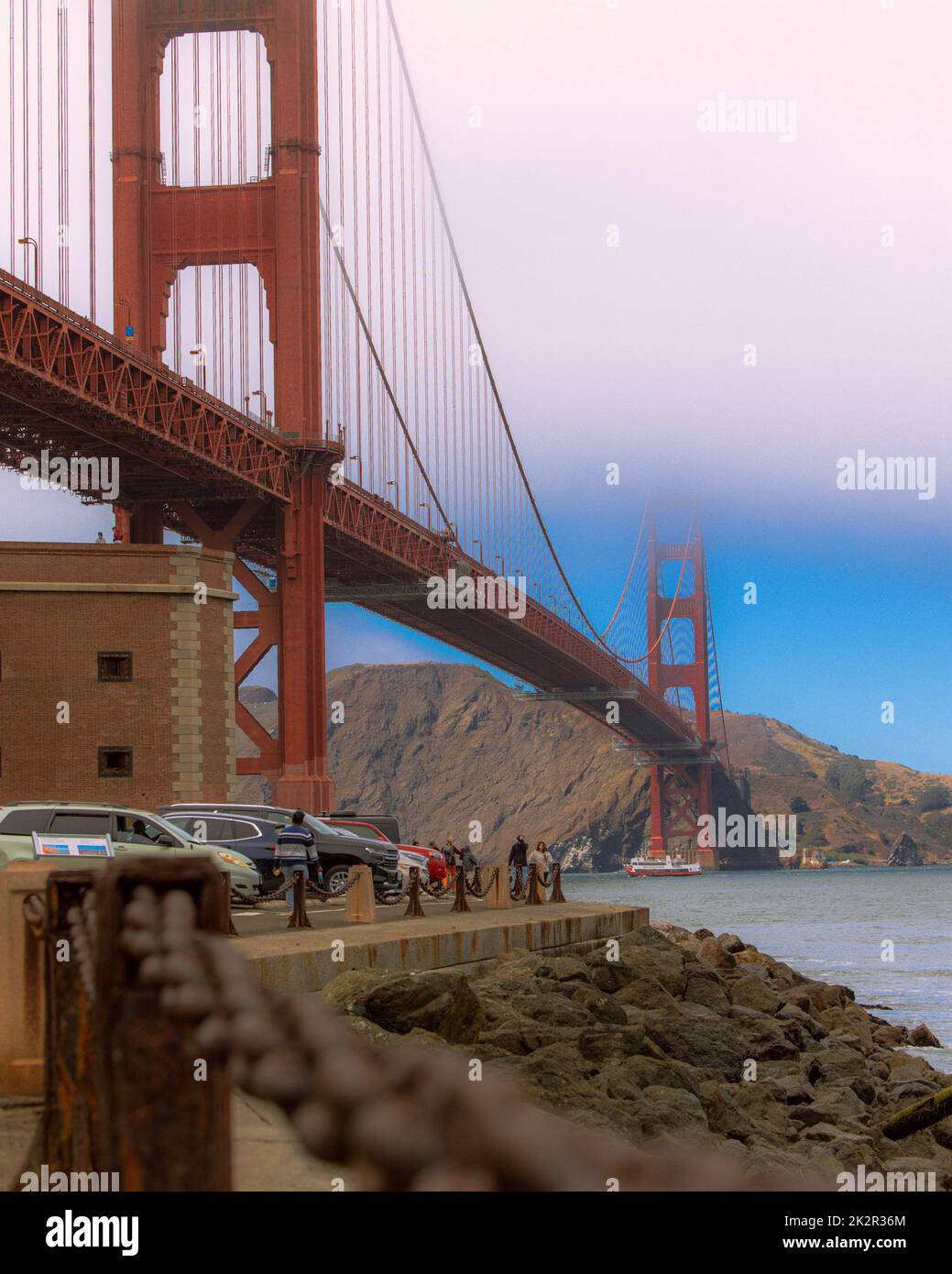 A vertical shot of the famous Golden Gate Bridge with visitors in San ...