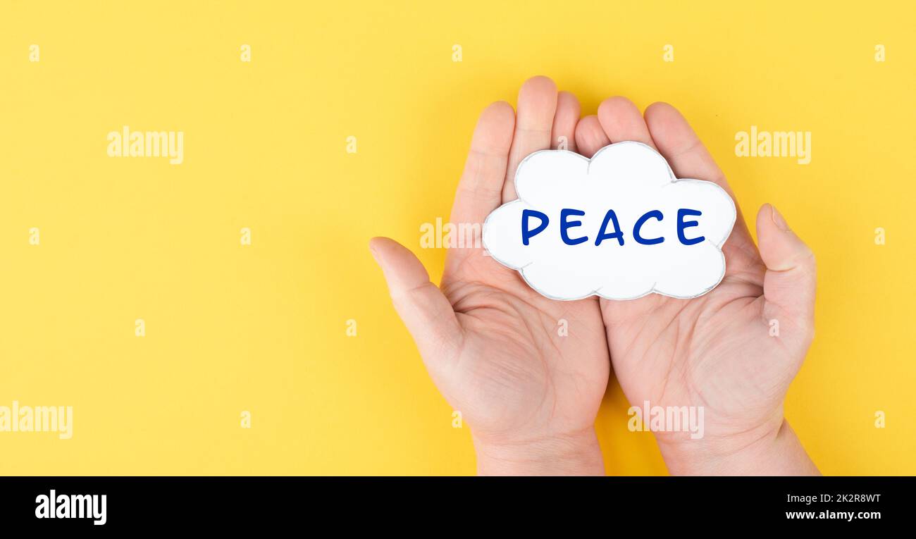 Holding a cloud with the word peace in the hands, stop war, support Ukraine, living peaceful together, color of ukrainian flag Stock Photo