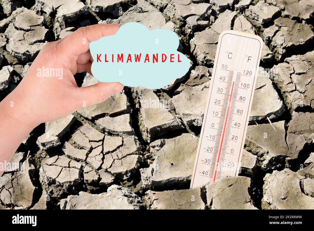 Dry earth with a thermometer, global warming concept, climate change is standing in german language on the cloud, environmental discussion, extreme weather Stock Photo